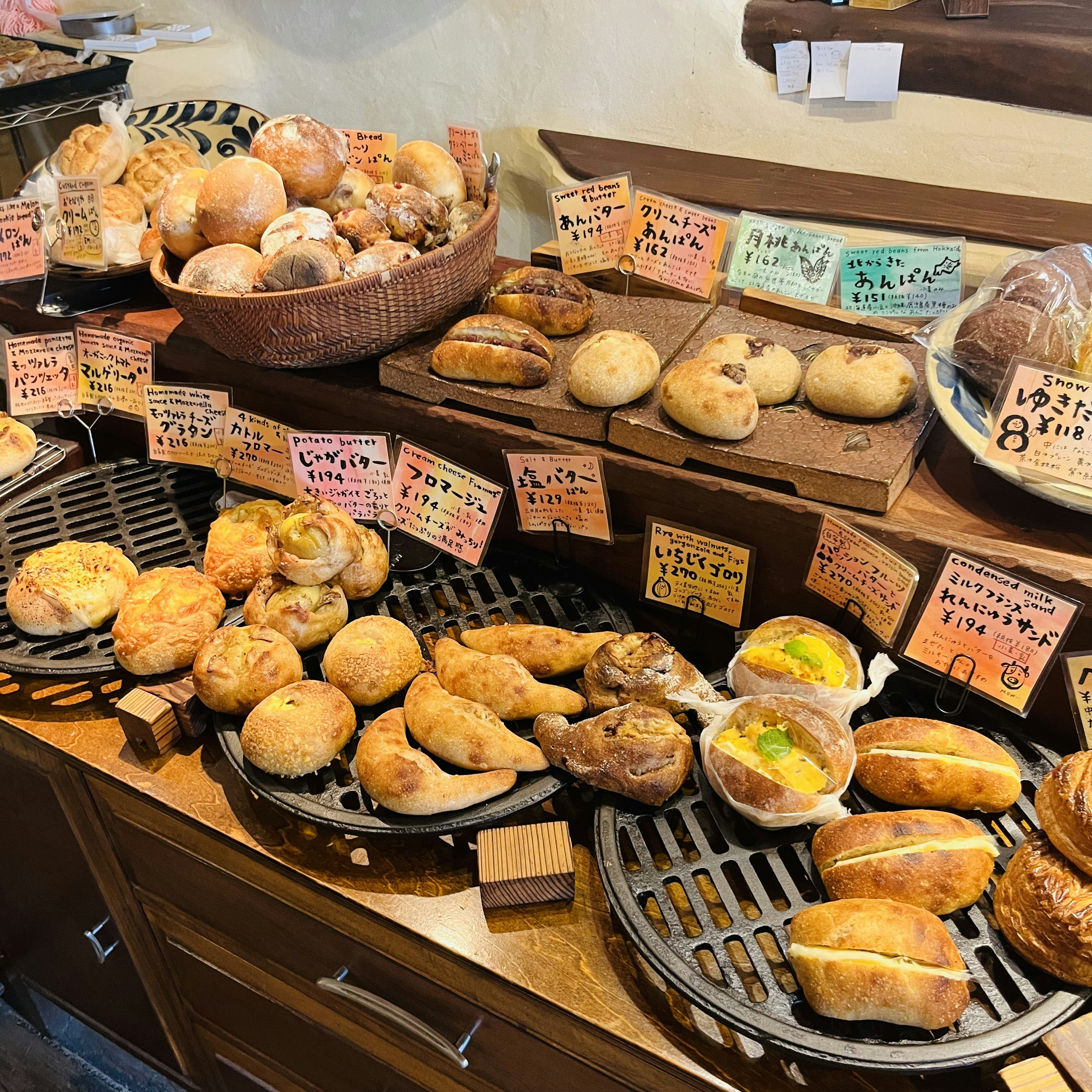 Un mostrador de panadería que muestra varios tipos de pan con etiquetas de precio coloridas