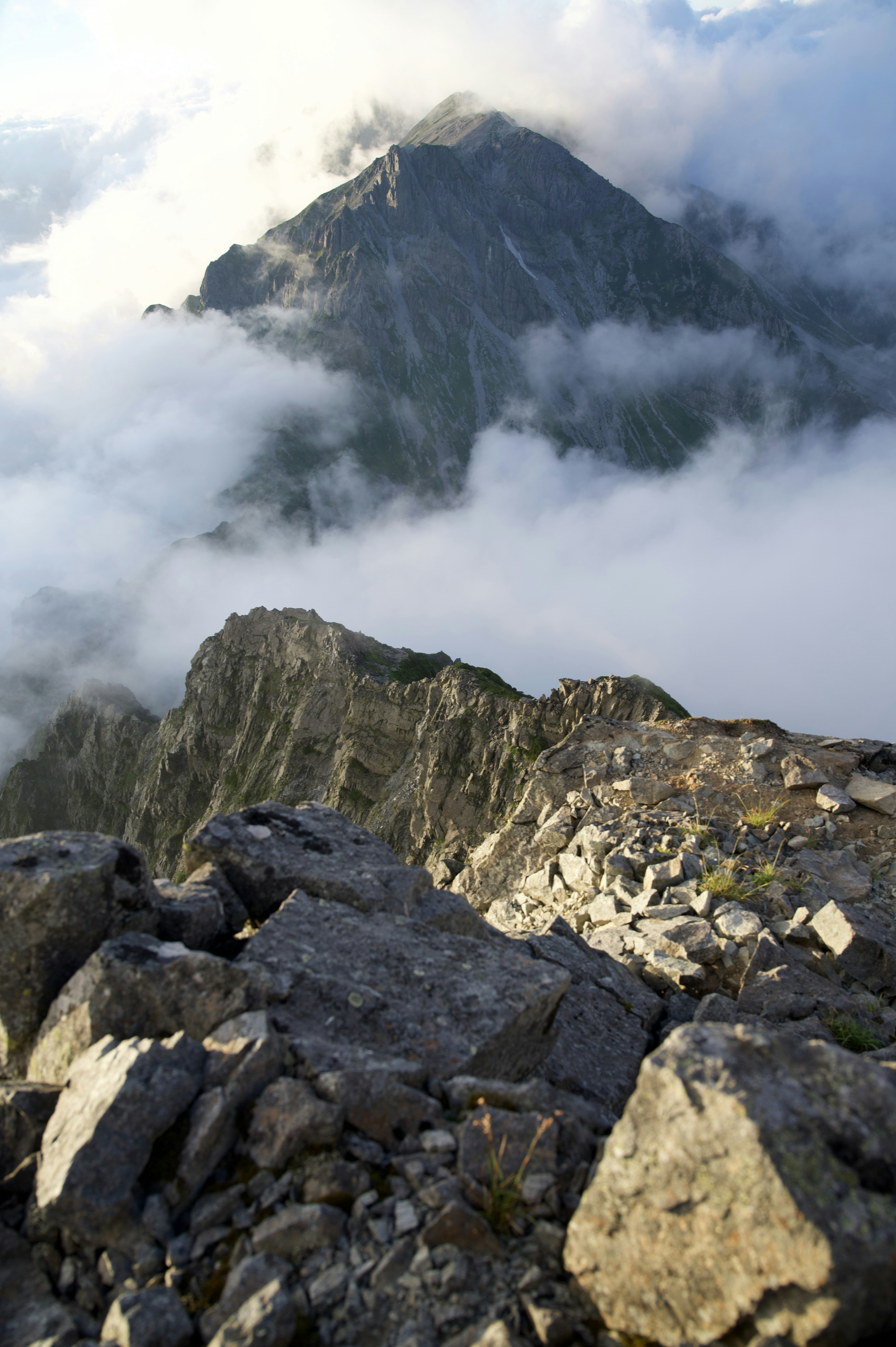 Vista panoramica di montagne coperte di nuvole con un primo piano roccioso