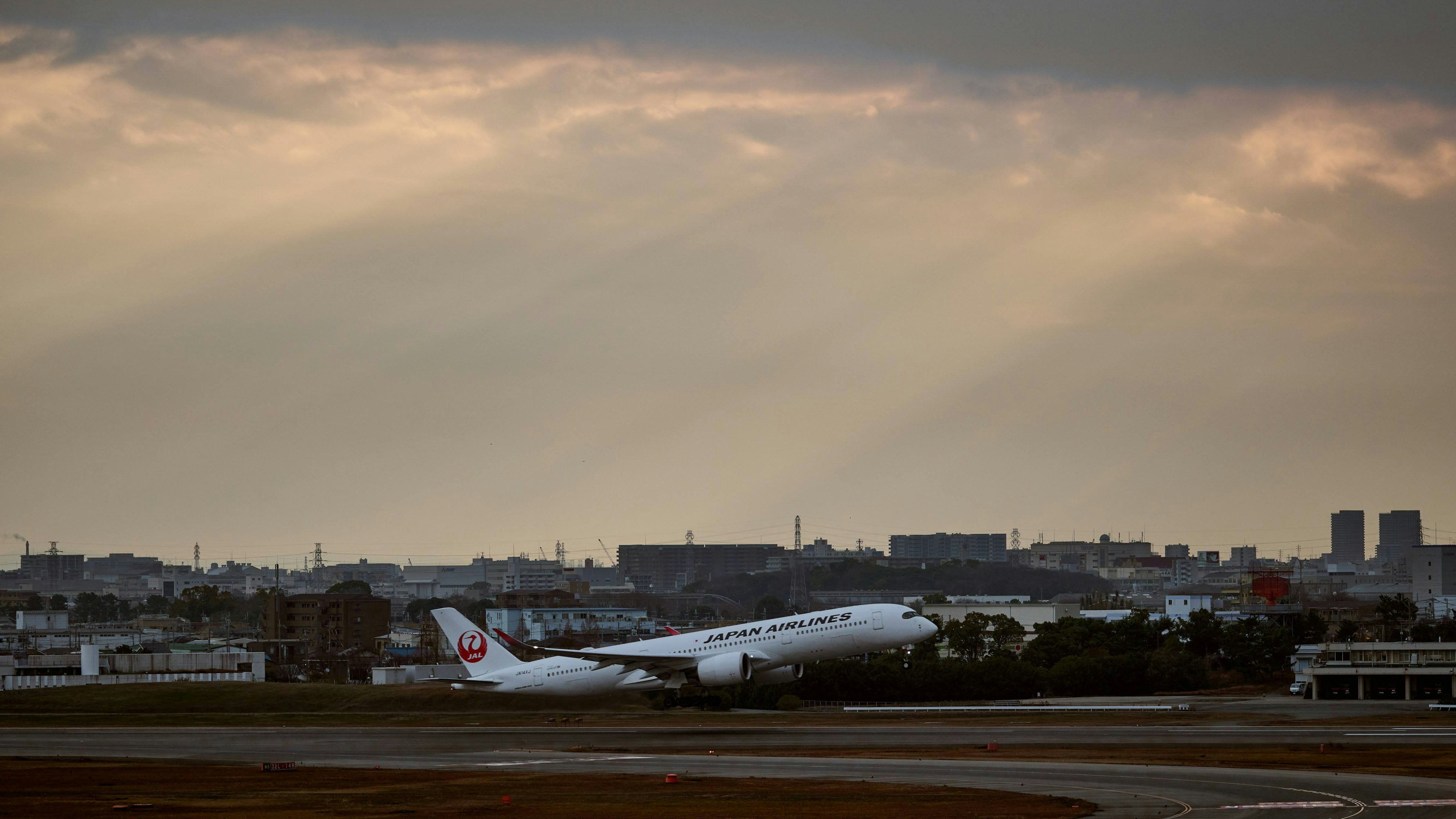 夕暮れ時の空港で離陸する航空機と都市の景観