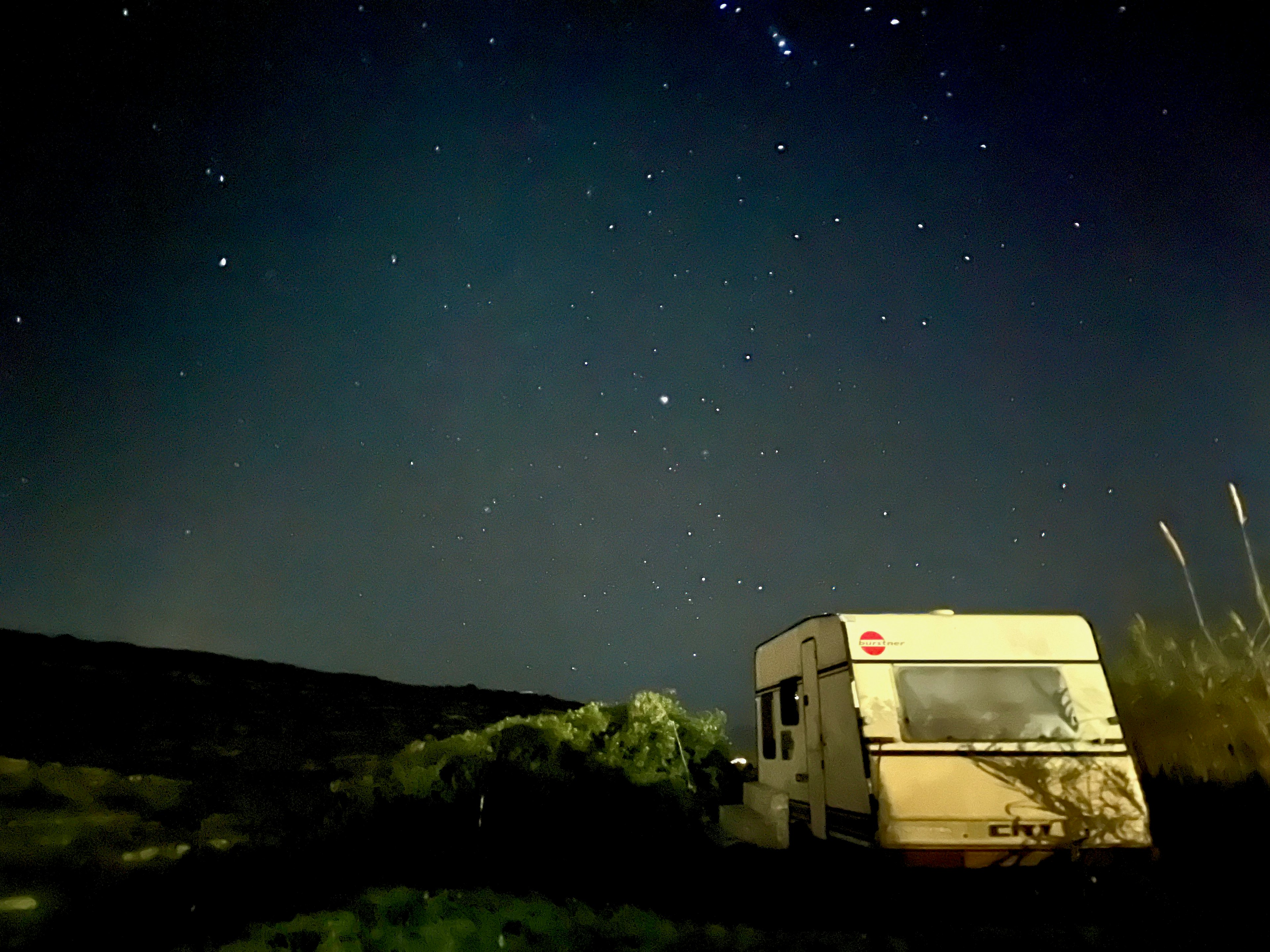 A camper van under a starry sky with surrounding nature