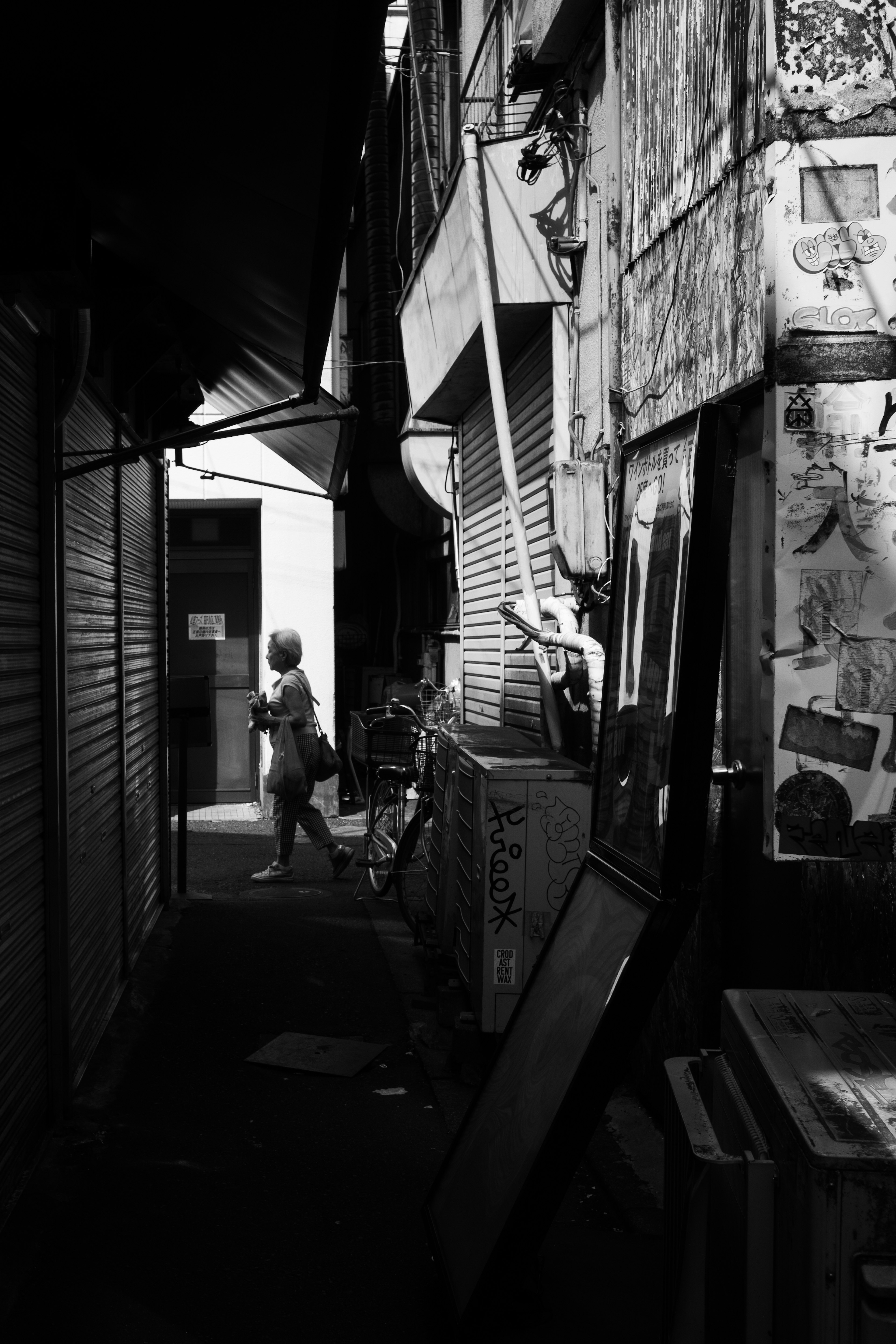 Silhouette d'une personne dans une ruelle étroite avec des affiches sur les murs environnants