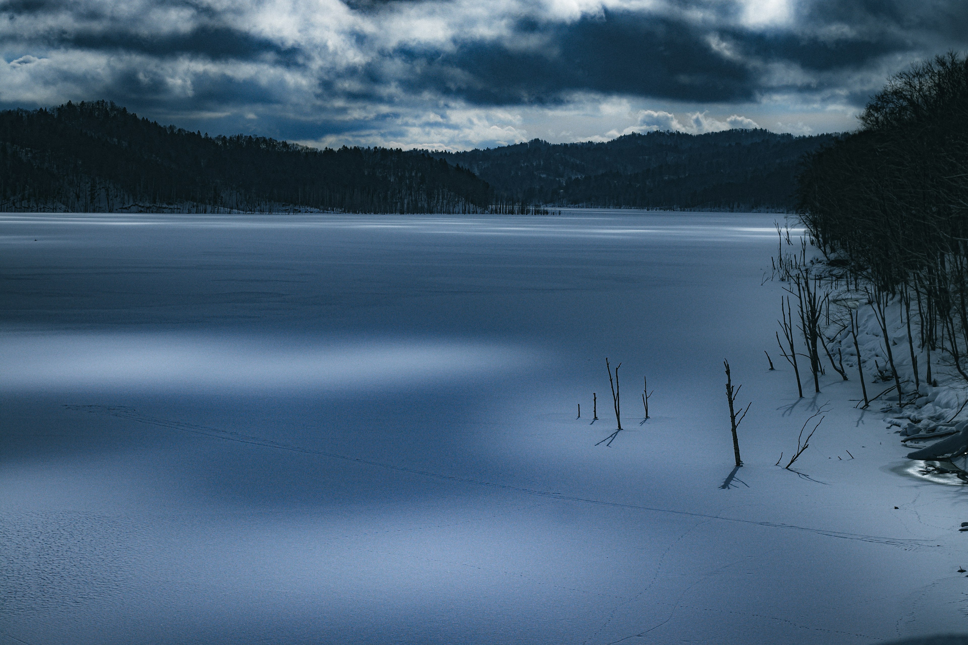 Serene lake landscape with dark clouds overhead reflecting on the calm water