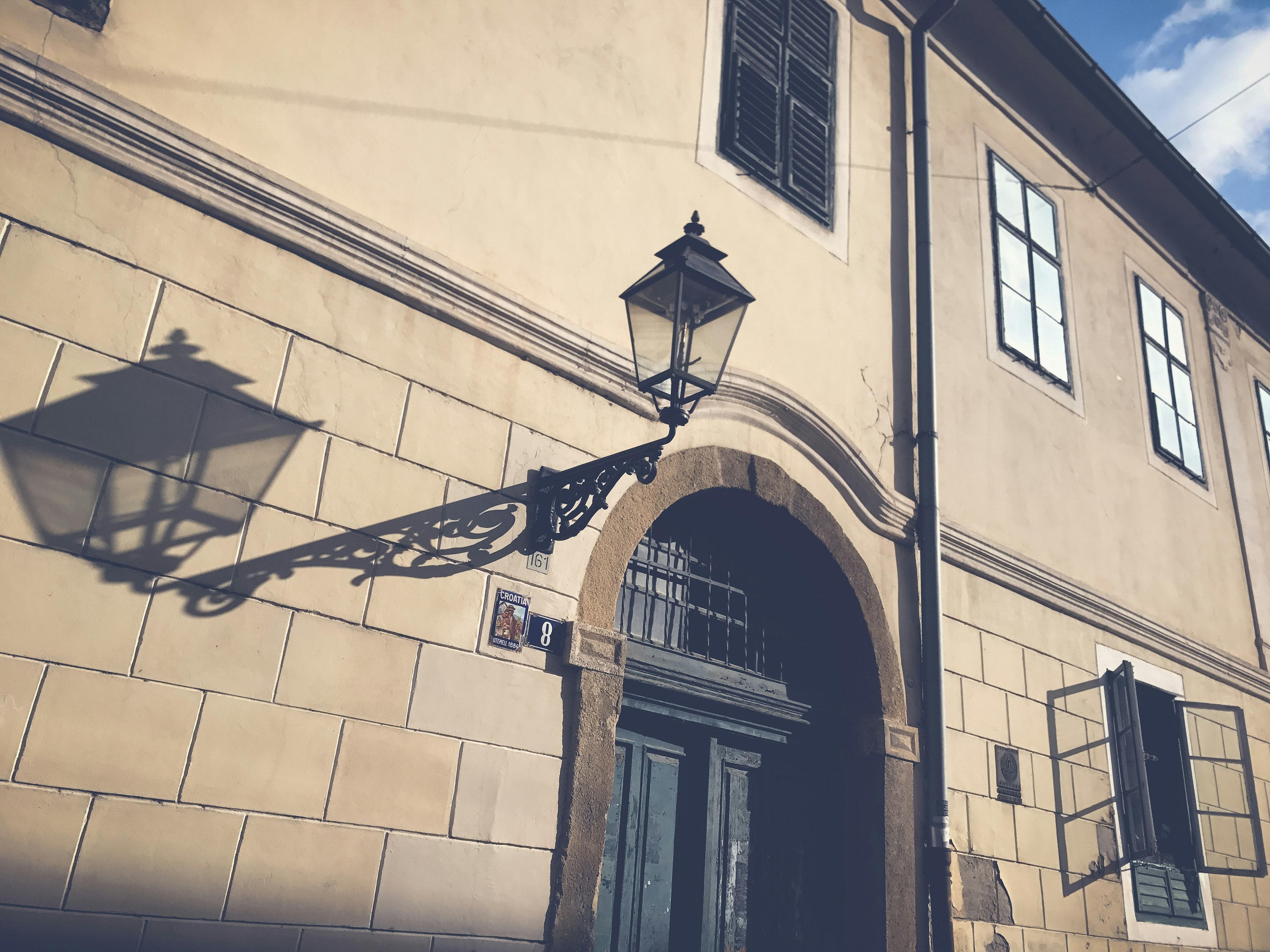 Exterior of a historic building featuring a vintage lamp and its shadow