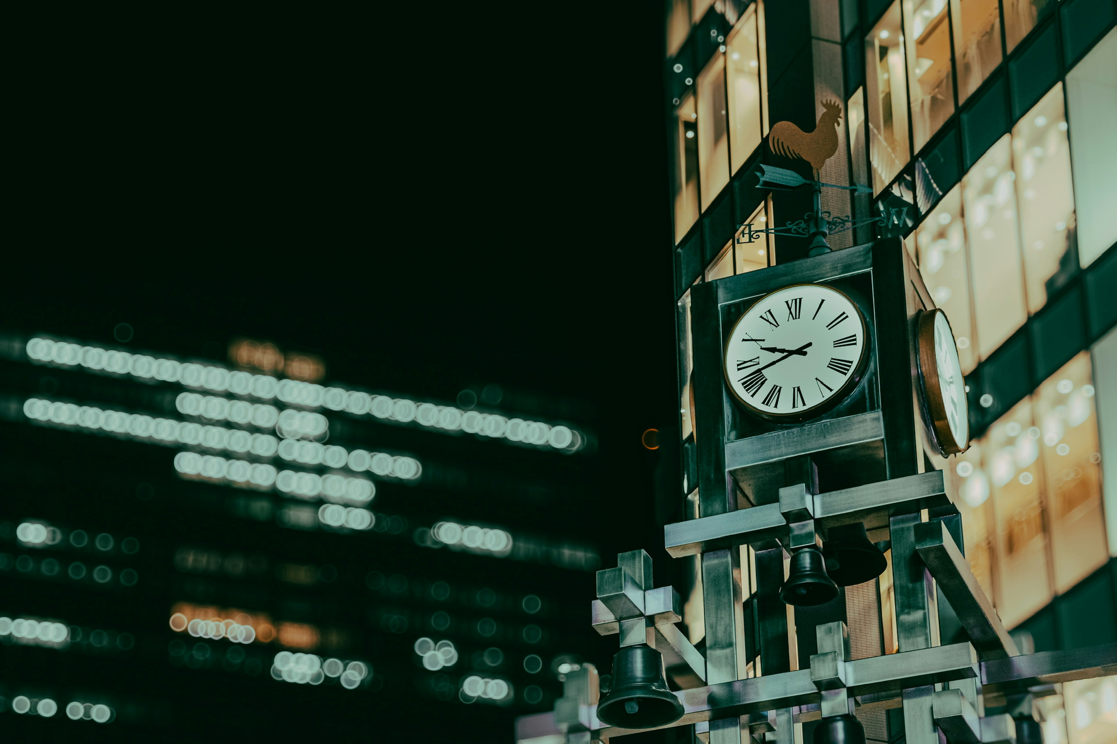 Reloj en un edificio de noche con luces de ciudad borrosas