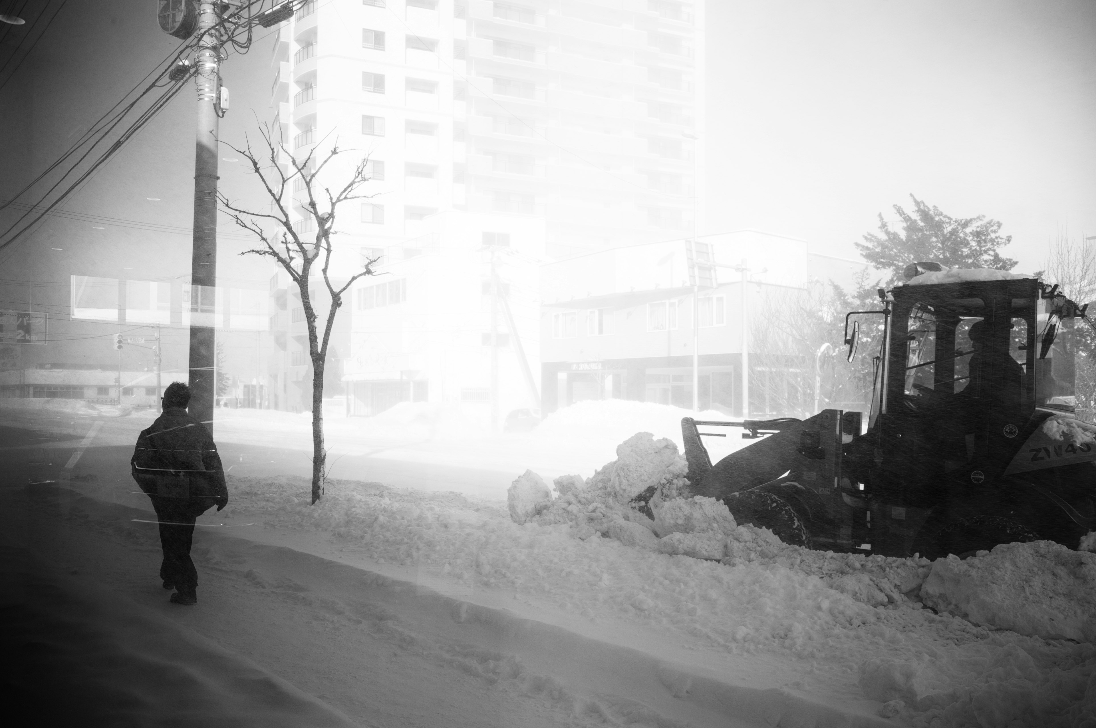 눈으로 덮인 거리를 걷는 사람과 제설기