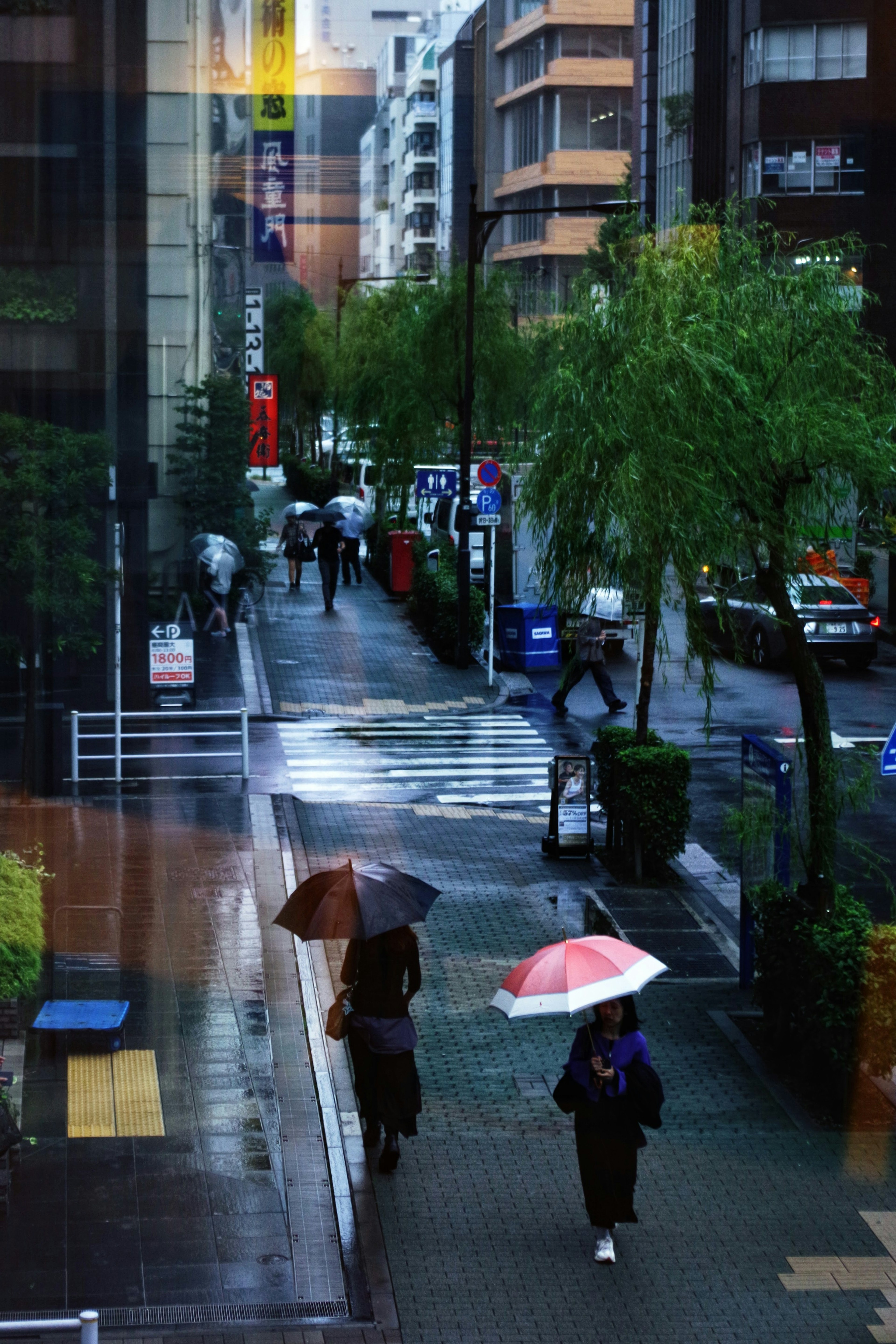 Personas caminando con paraguas en una calle lluviosa de Tokio