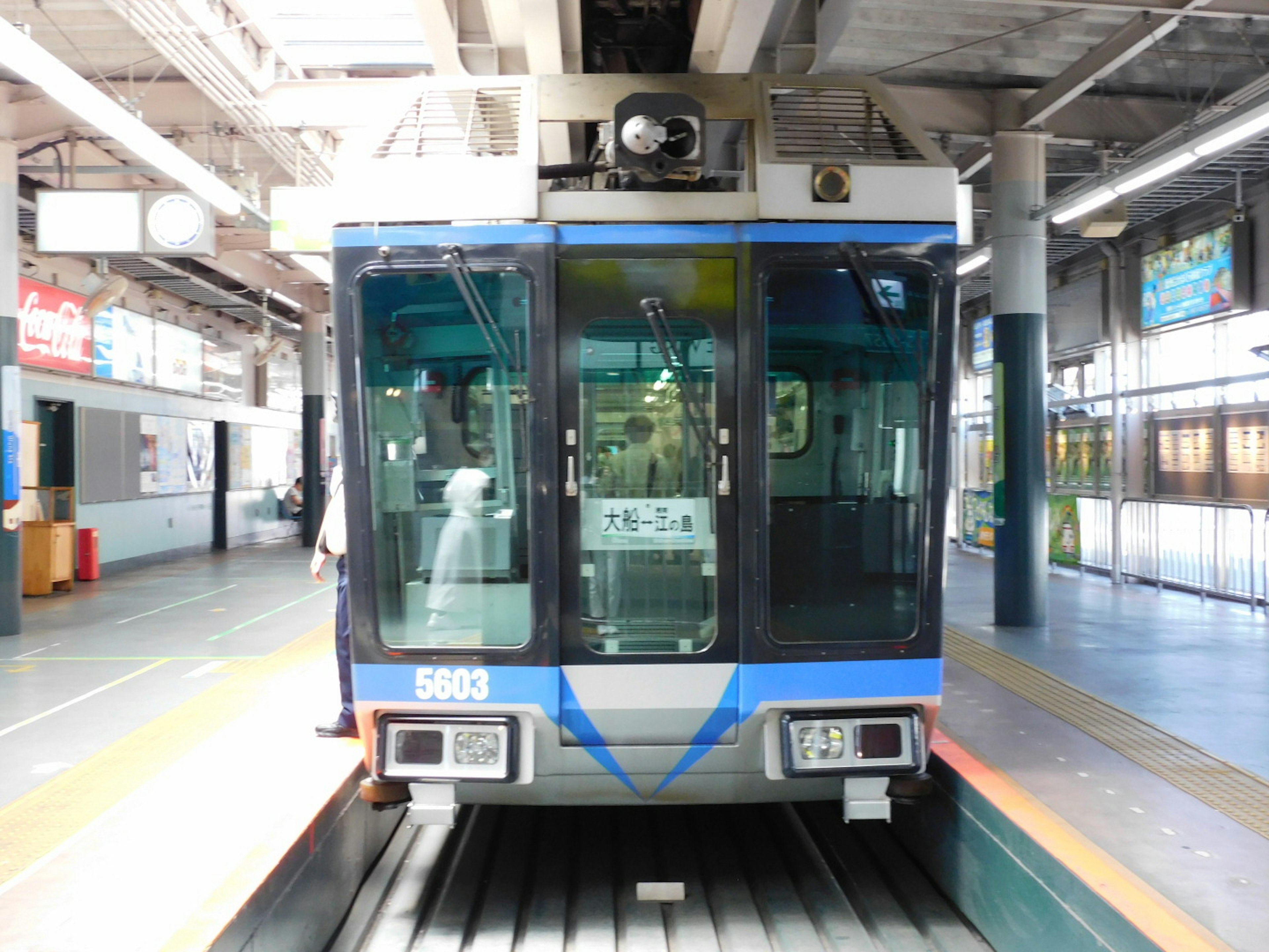 Vista frontal de un tren azul y blanco en una estación