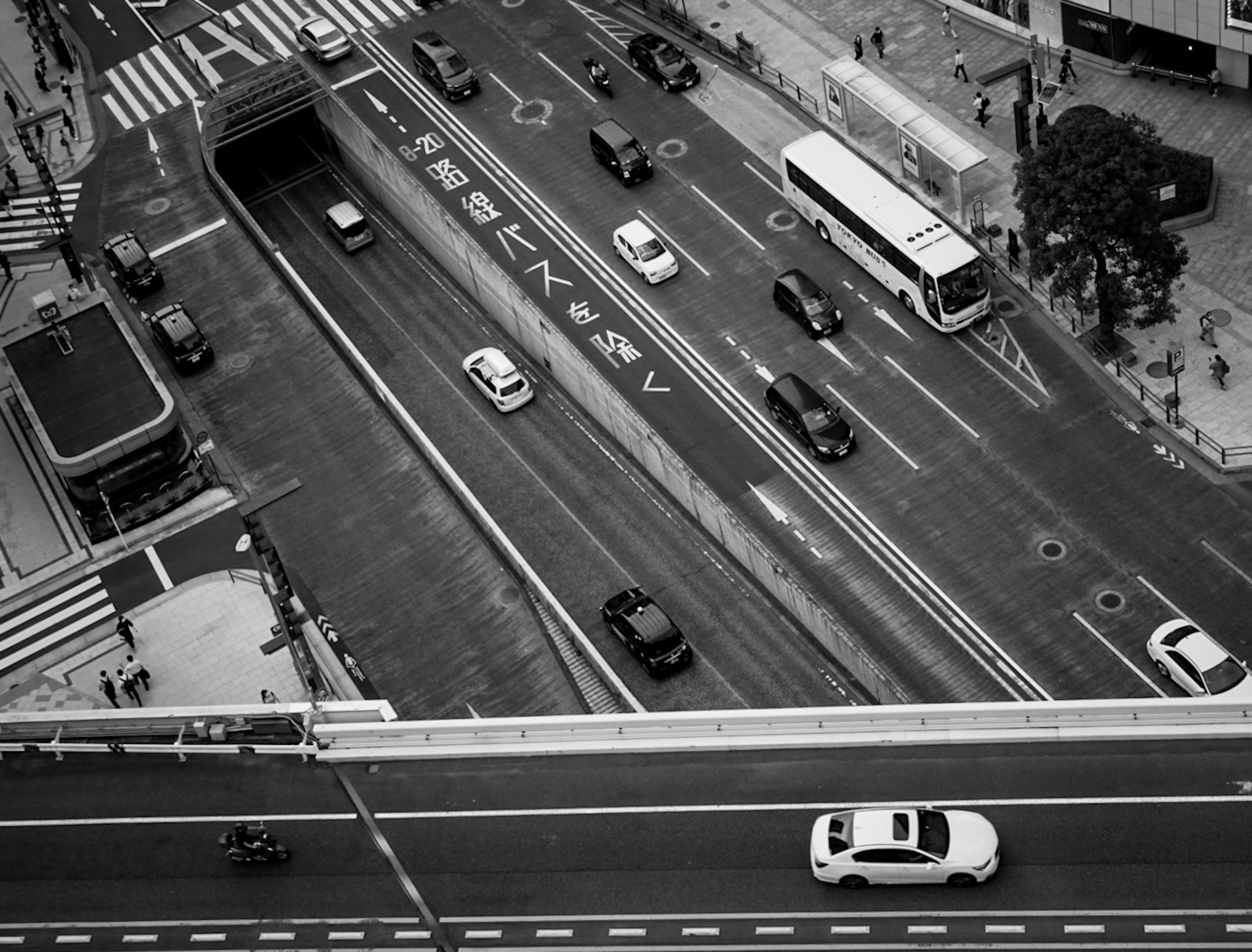 高層ビルからの視点で見た都市の交通で、モノクロの車両と交差点が描かれている