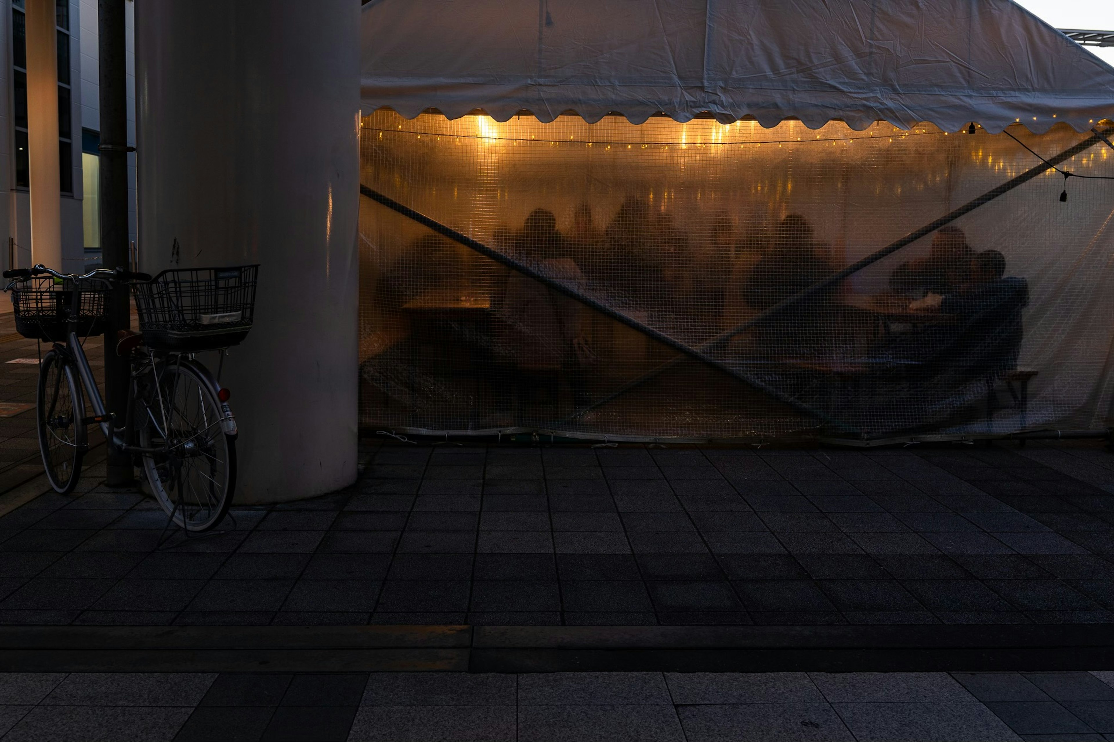 Silhouettes de personnes à l'intérieur d'une tente dans un environnement sombre avec une bicyclette