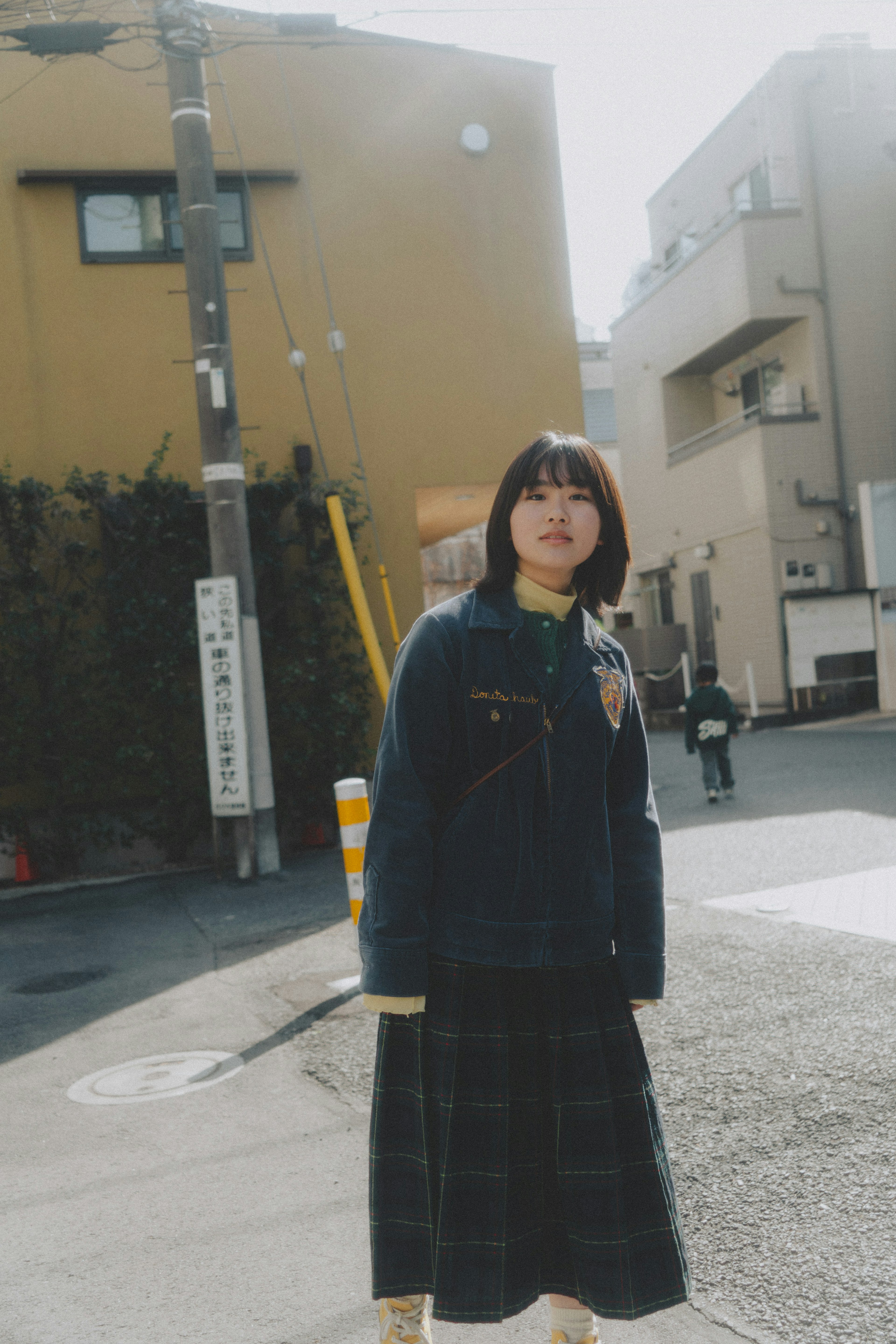 A woman standing at a street corner during the day