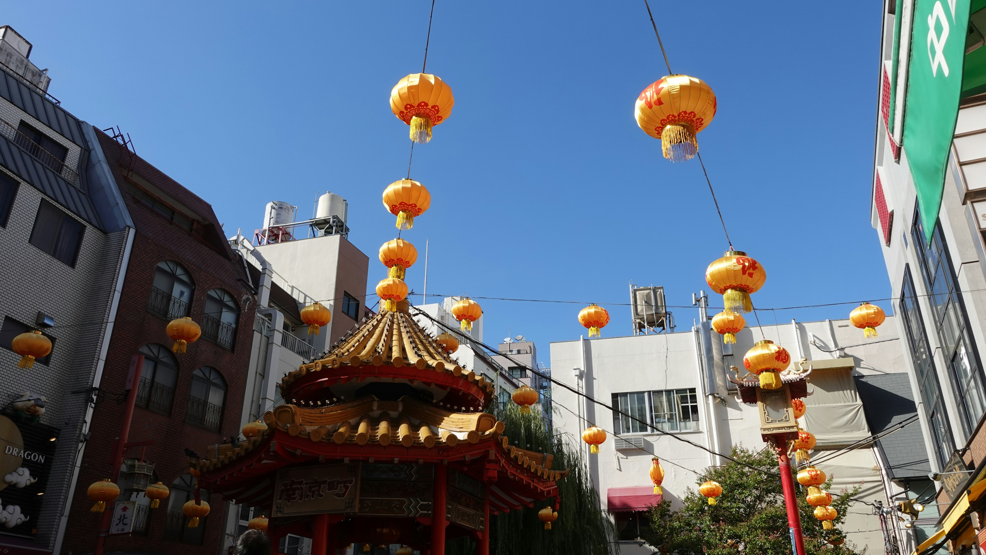 Orange Laternen hängen unter einem blauen Himmel mit traditioneller Architektur