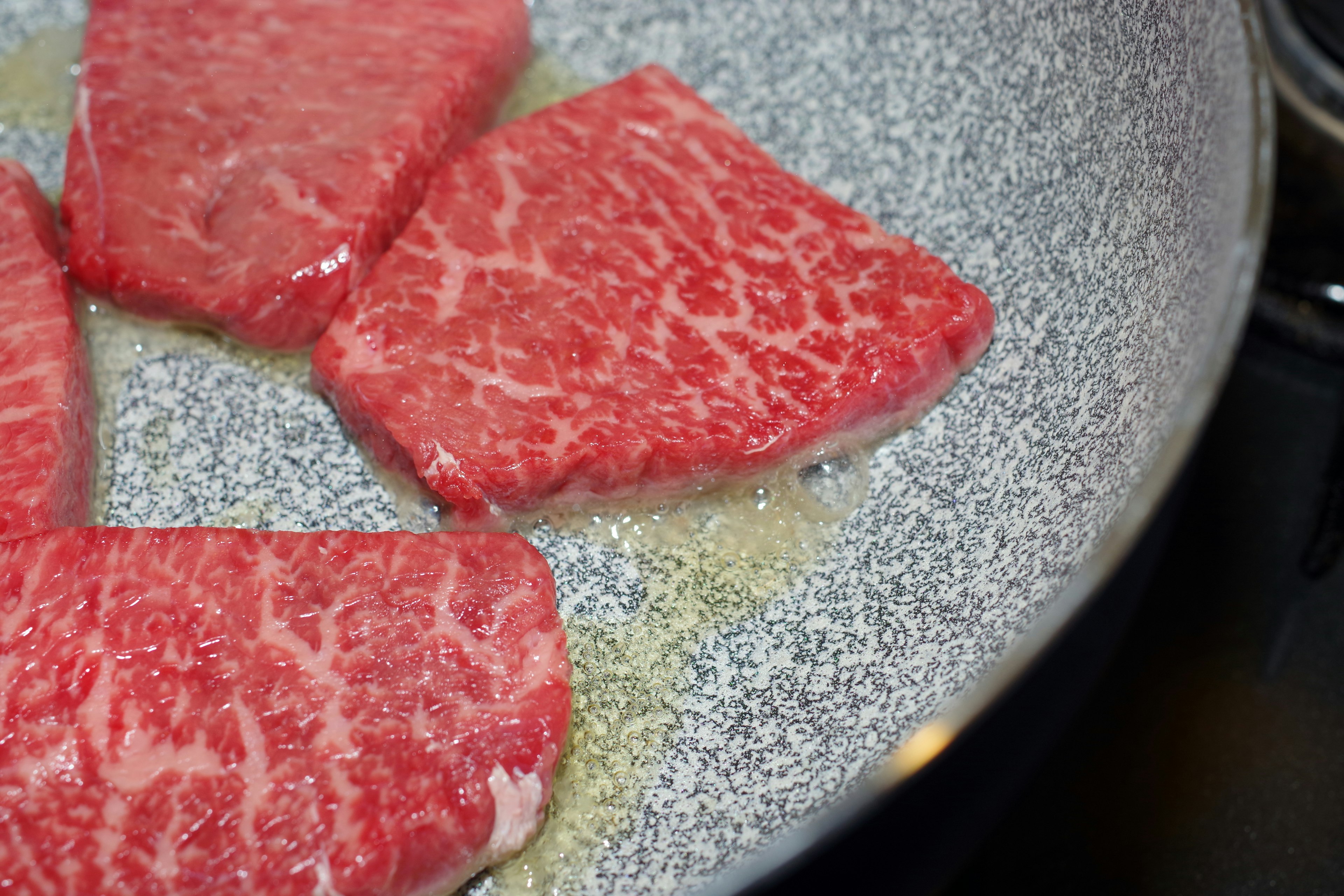 Piezas de steak Wagyu chisporroteando en una sartén