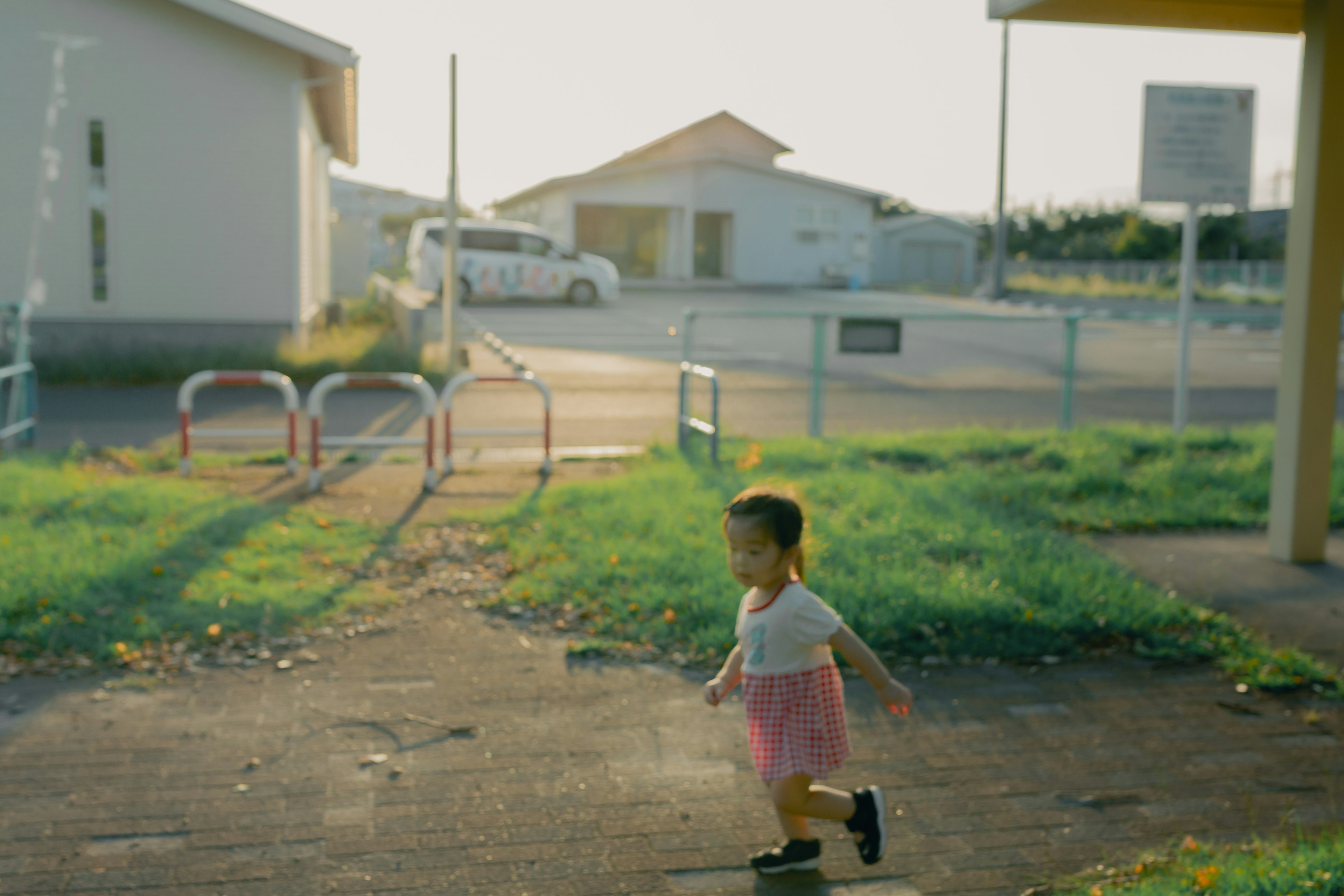 子供が公園で走っている風景 背景には住宅と車が見える