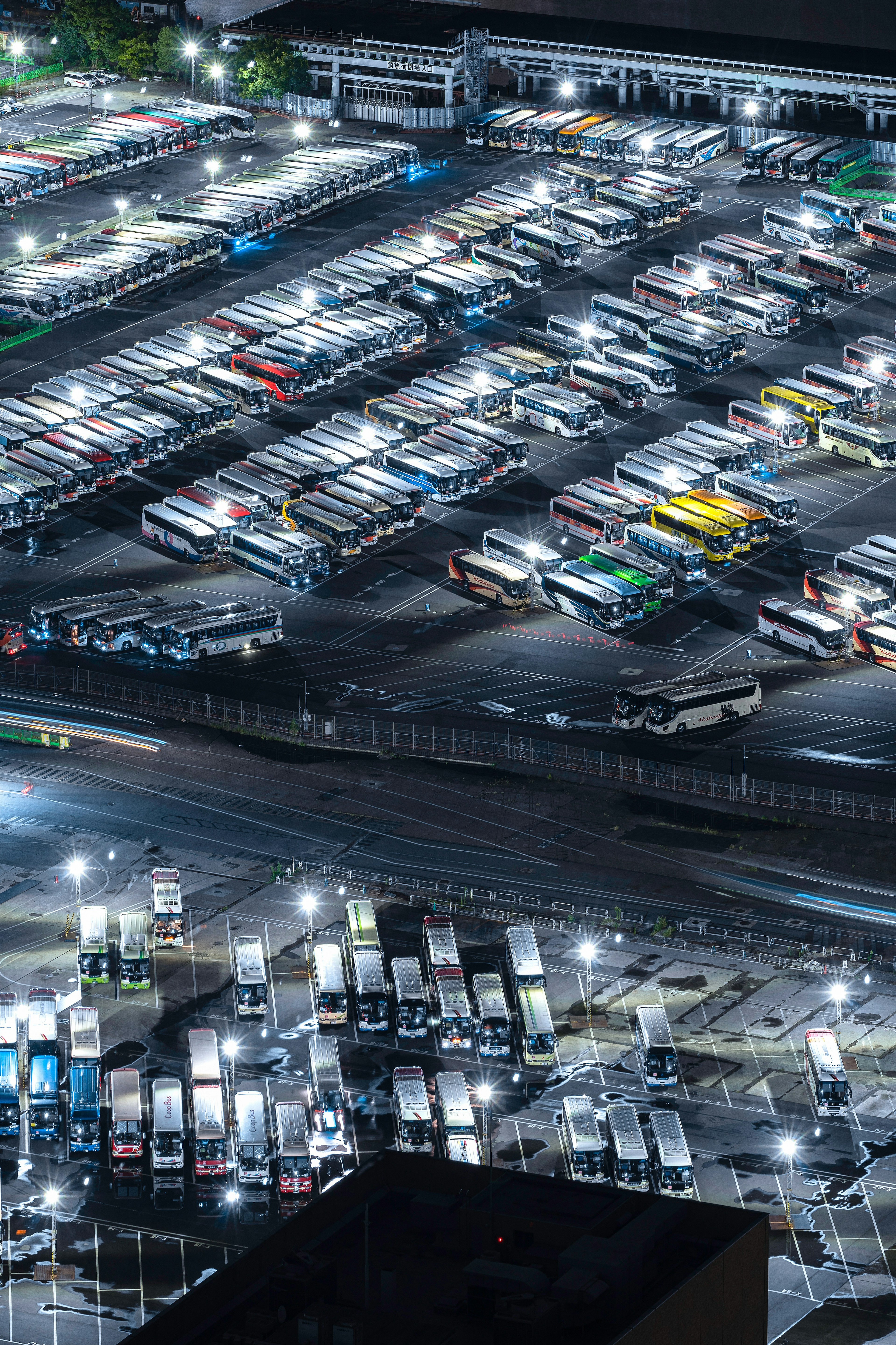 Aerial view of a bus depot at night with numerous buses parked in organized rows