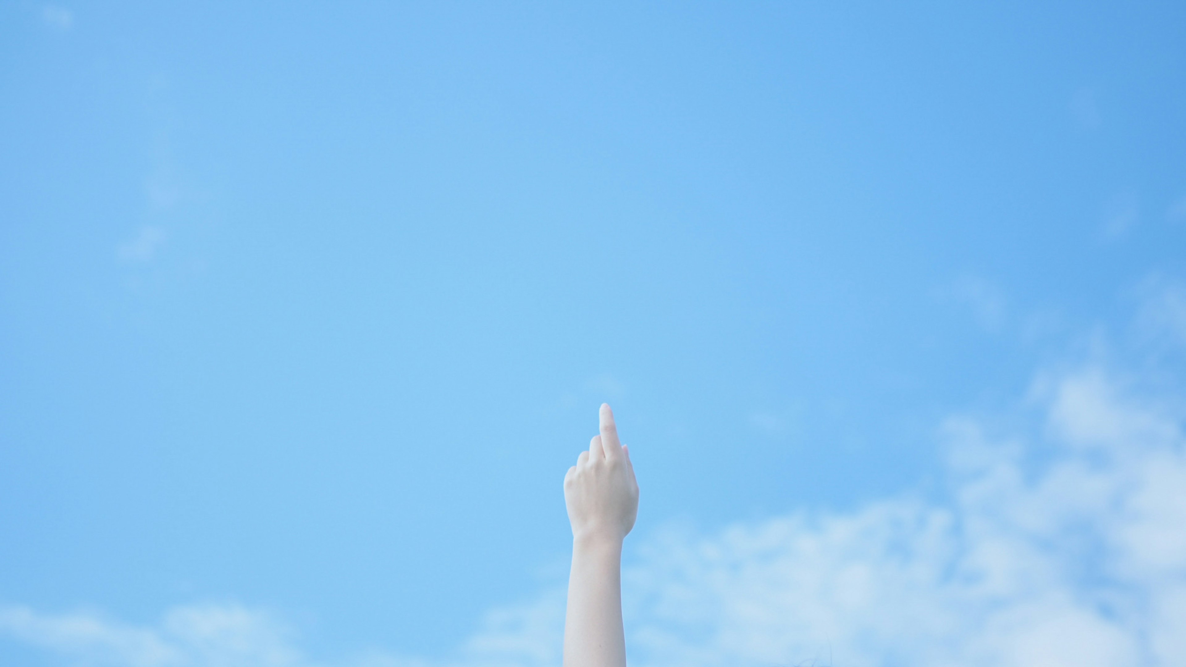 Hand pointing towards the blue sky