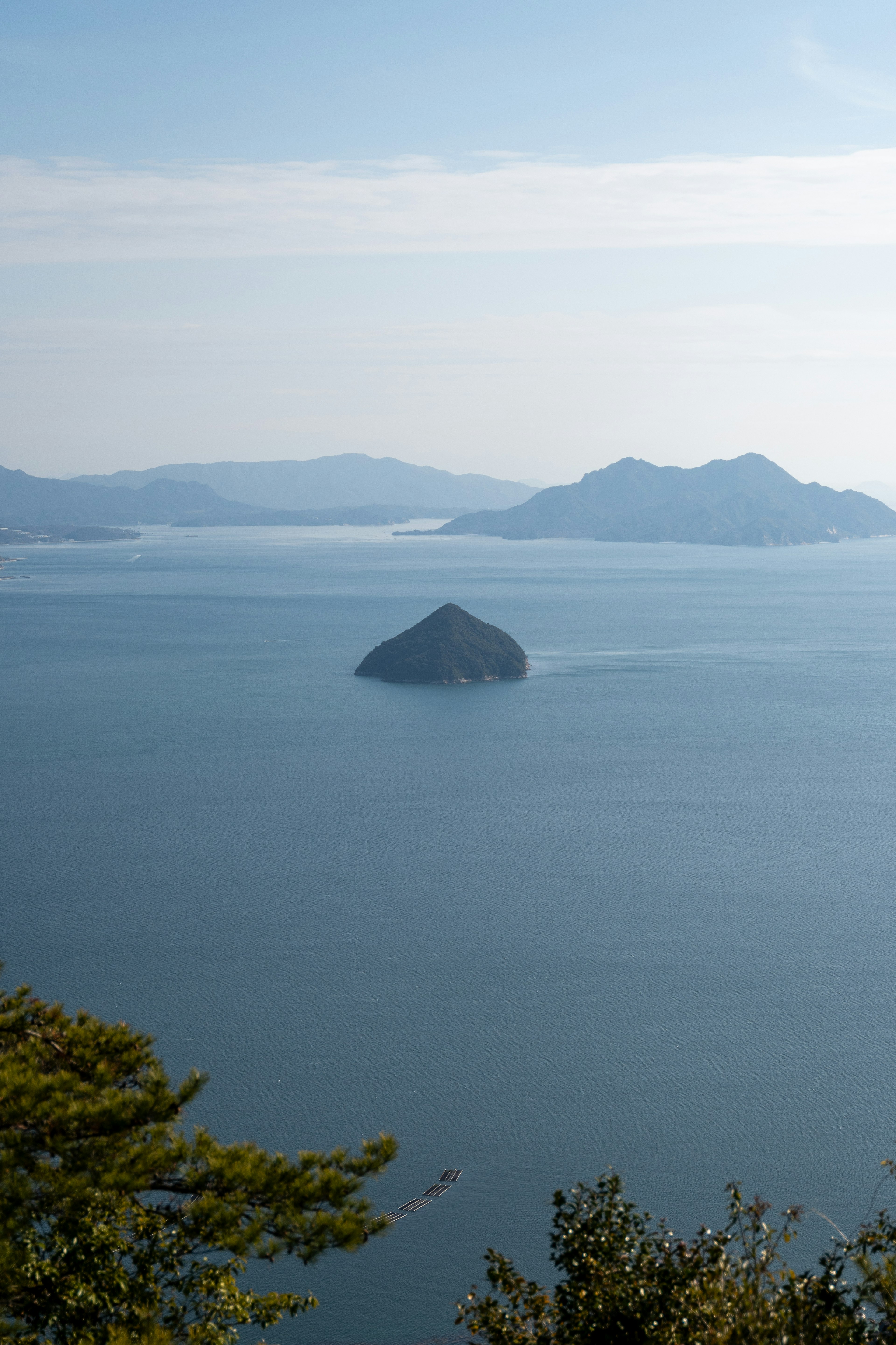 Eine kleine Insel im Meer umgeben von fernen Bergen