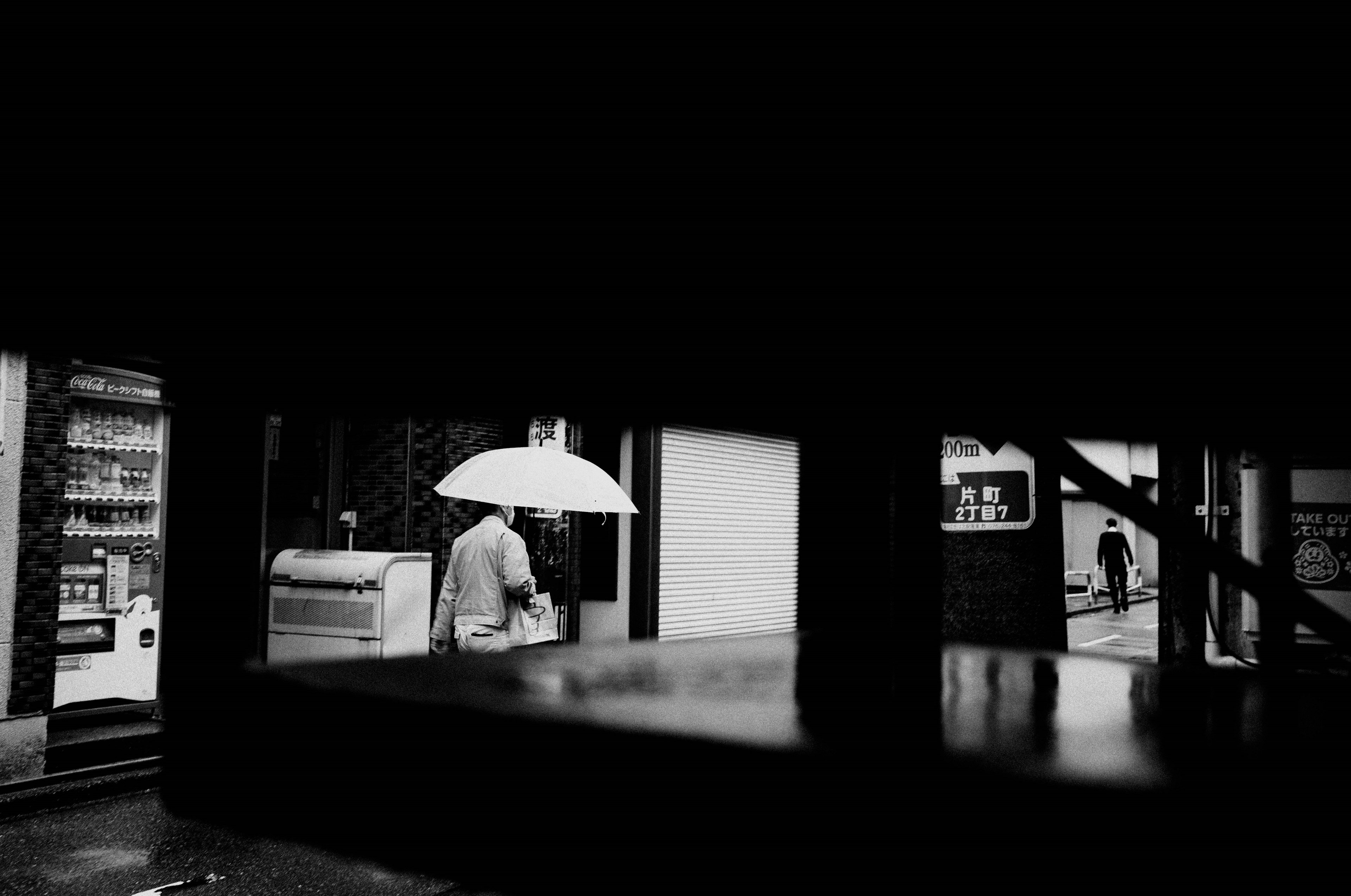 Black and white street scene with a person holding an umbrella