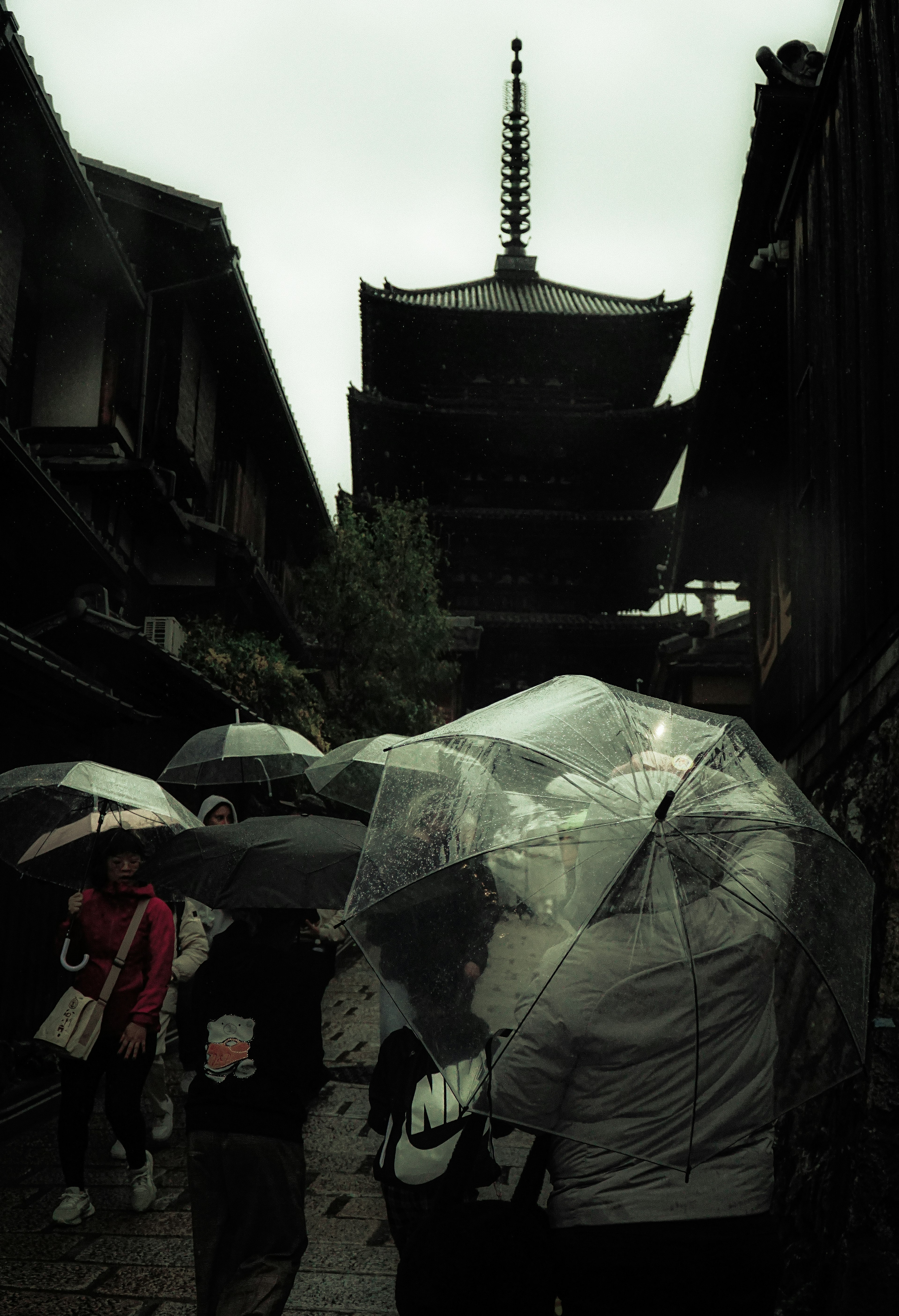 Des personnes avec des parapluies sous la pluie près d'une pagode