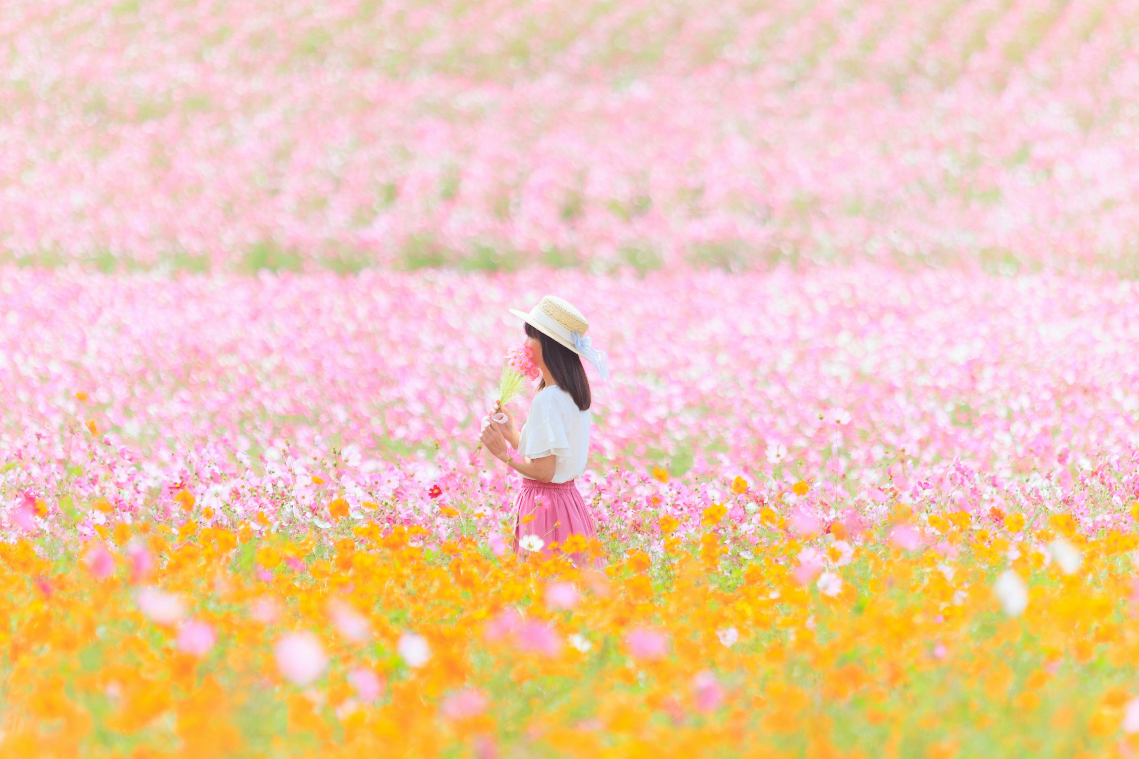 色とりどりの花が広がるフィールドで立つ女性