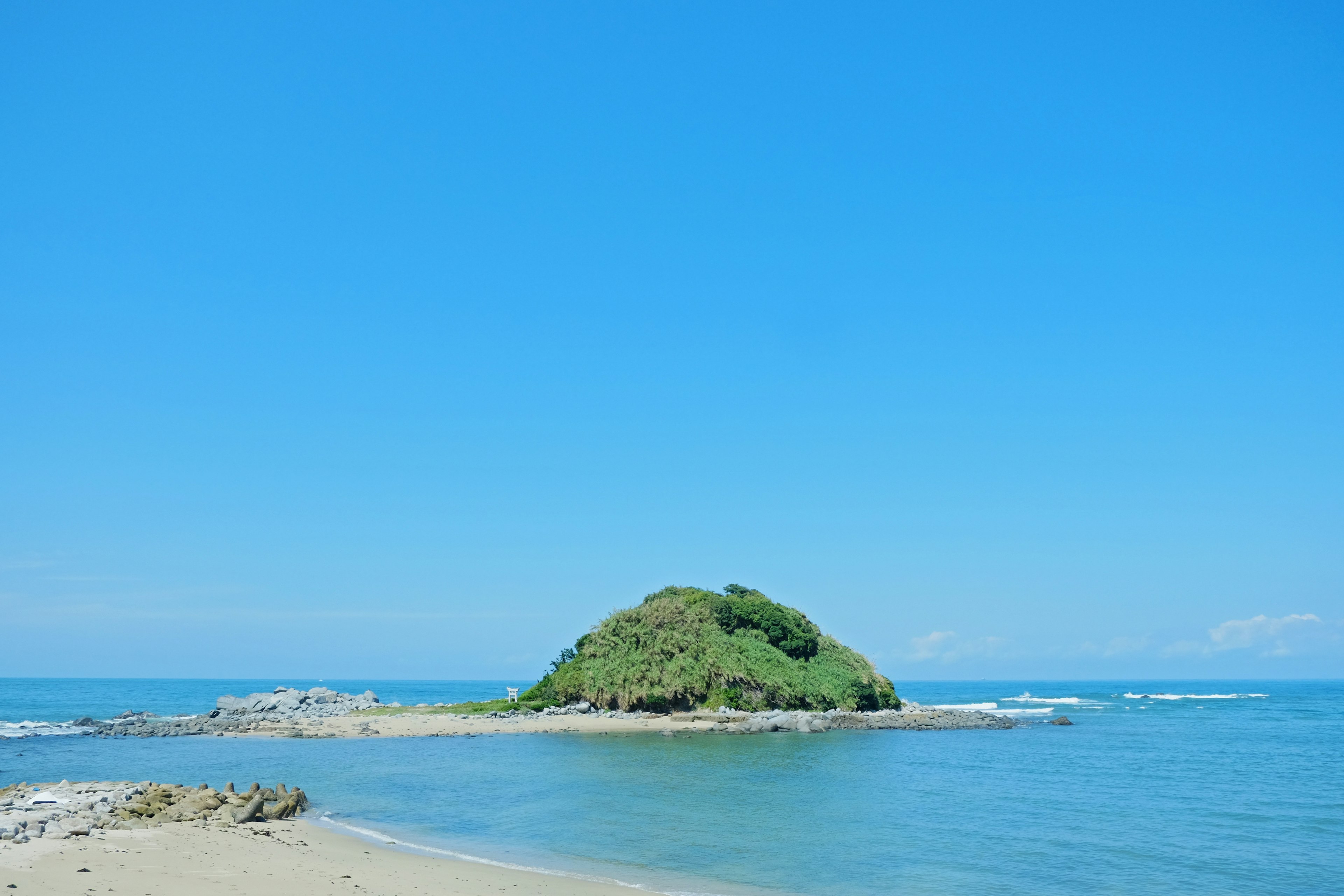 青空と海に囲まれた緑の小島の風景