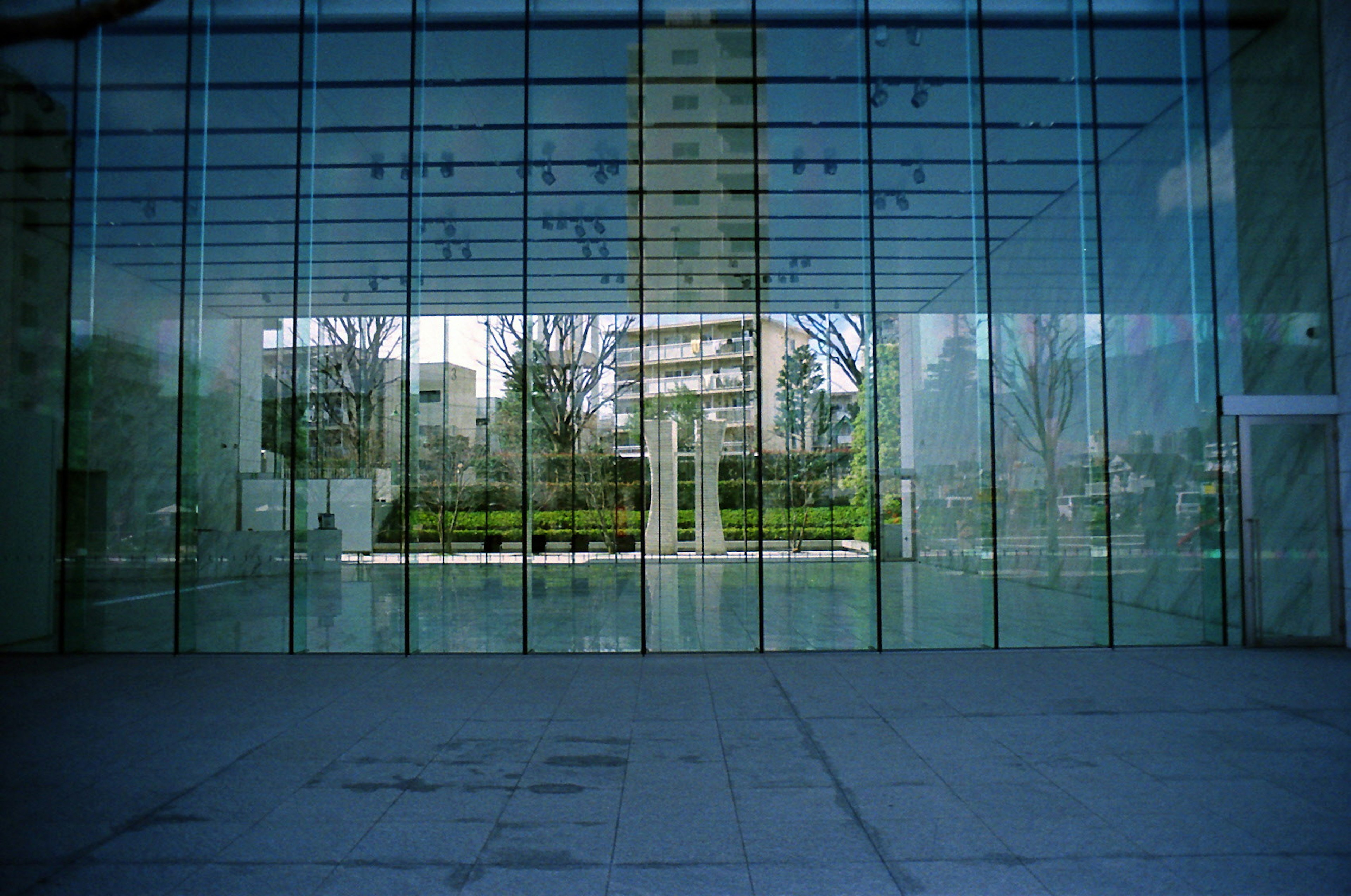 Image capturing the reflection of a garden in front of a glass building