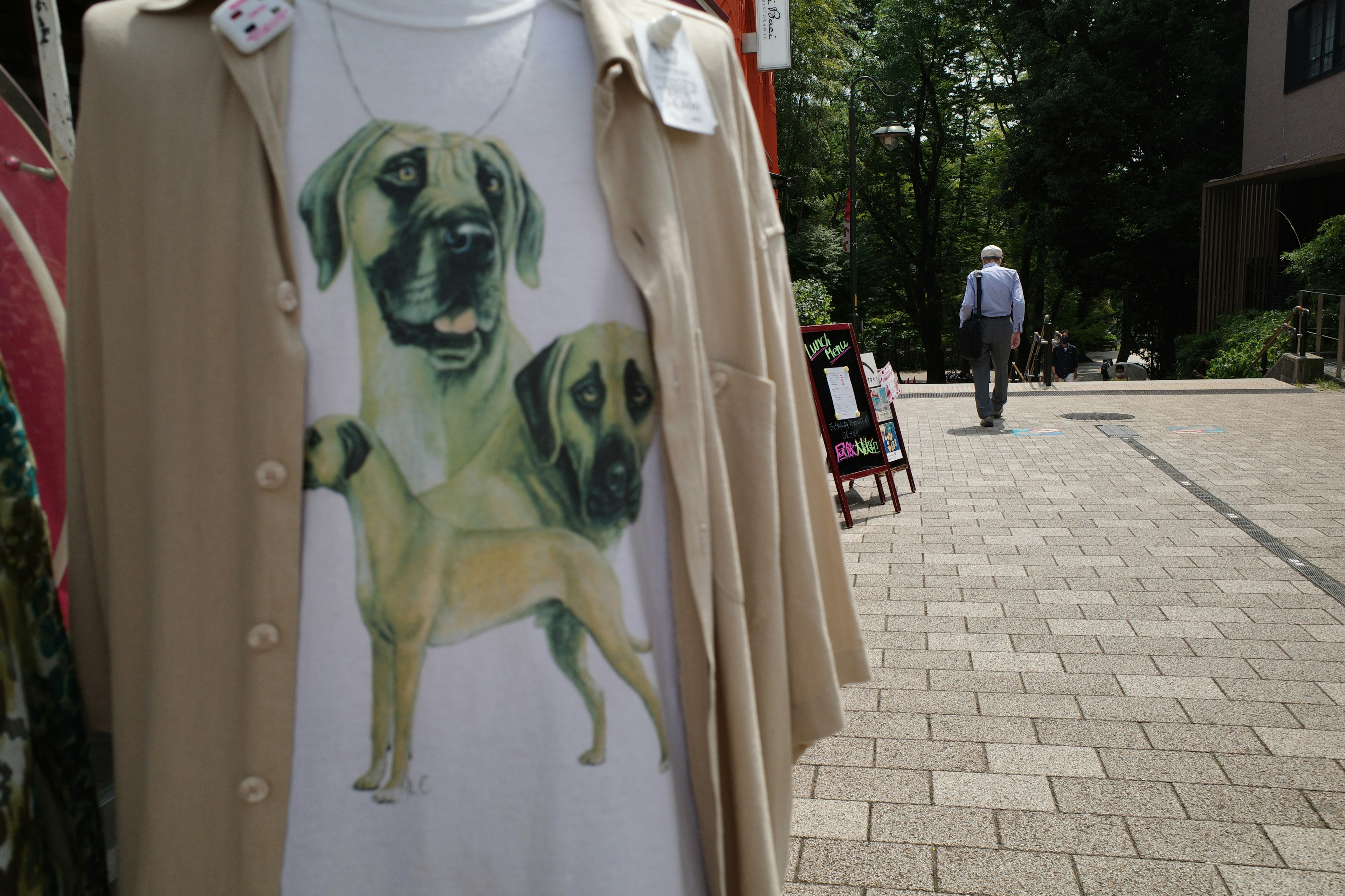 Ein weißes T-Shirt mit Hundebildern, das vor einem Boutique hängt