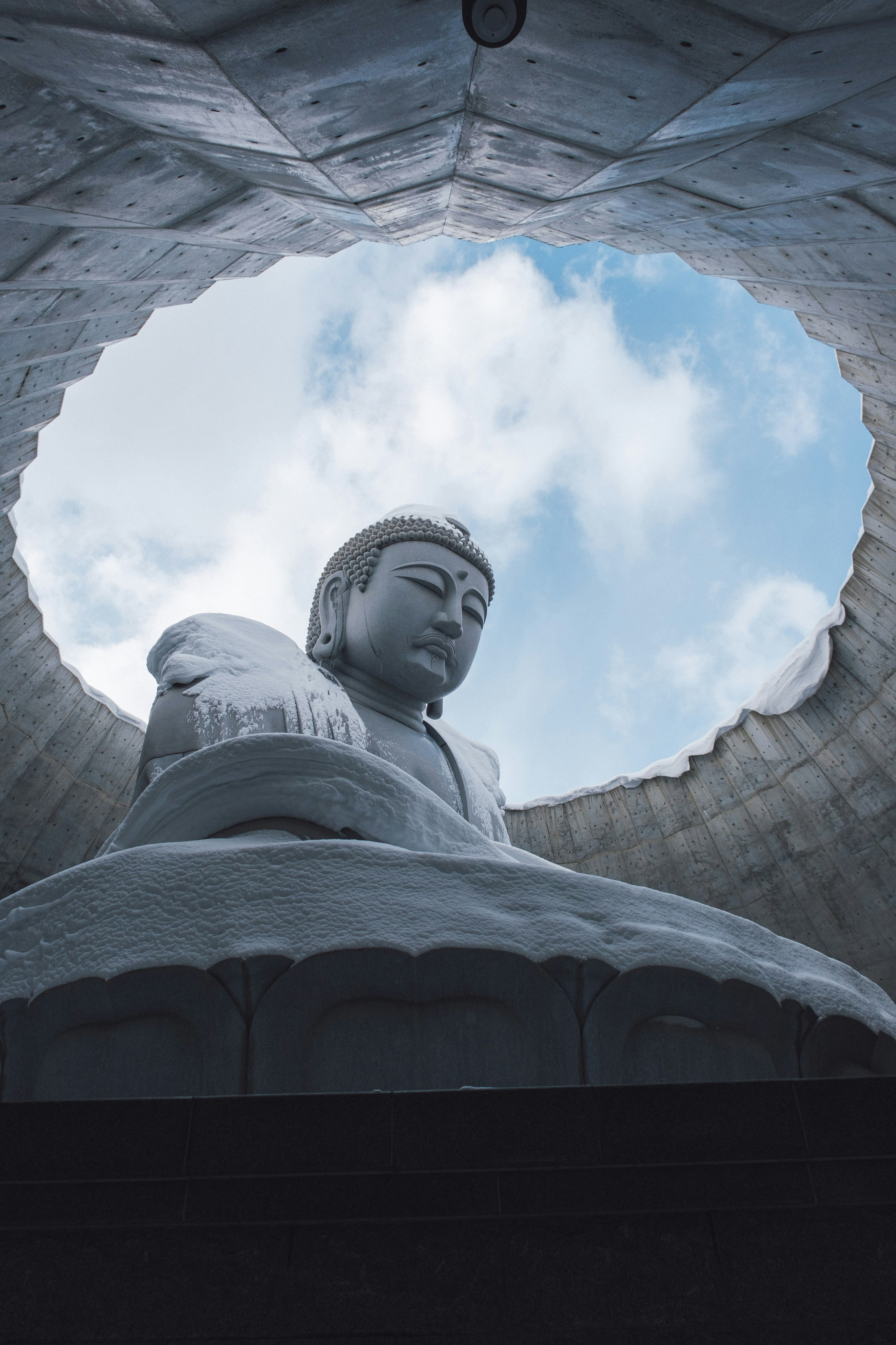 View of a large Buddha statue from below with a sky background