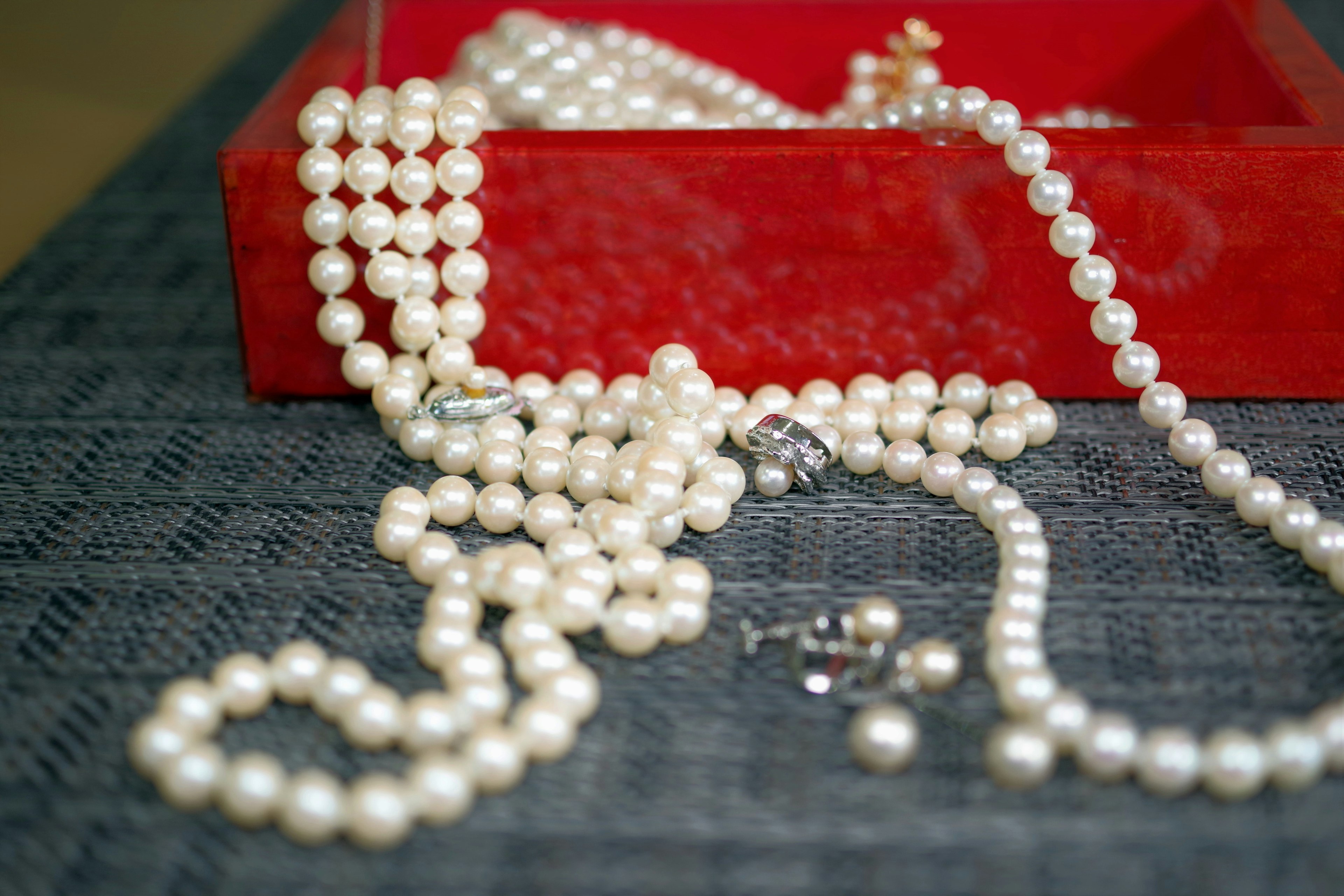 Pearl necklaces scattered on a red box