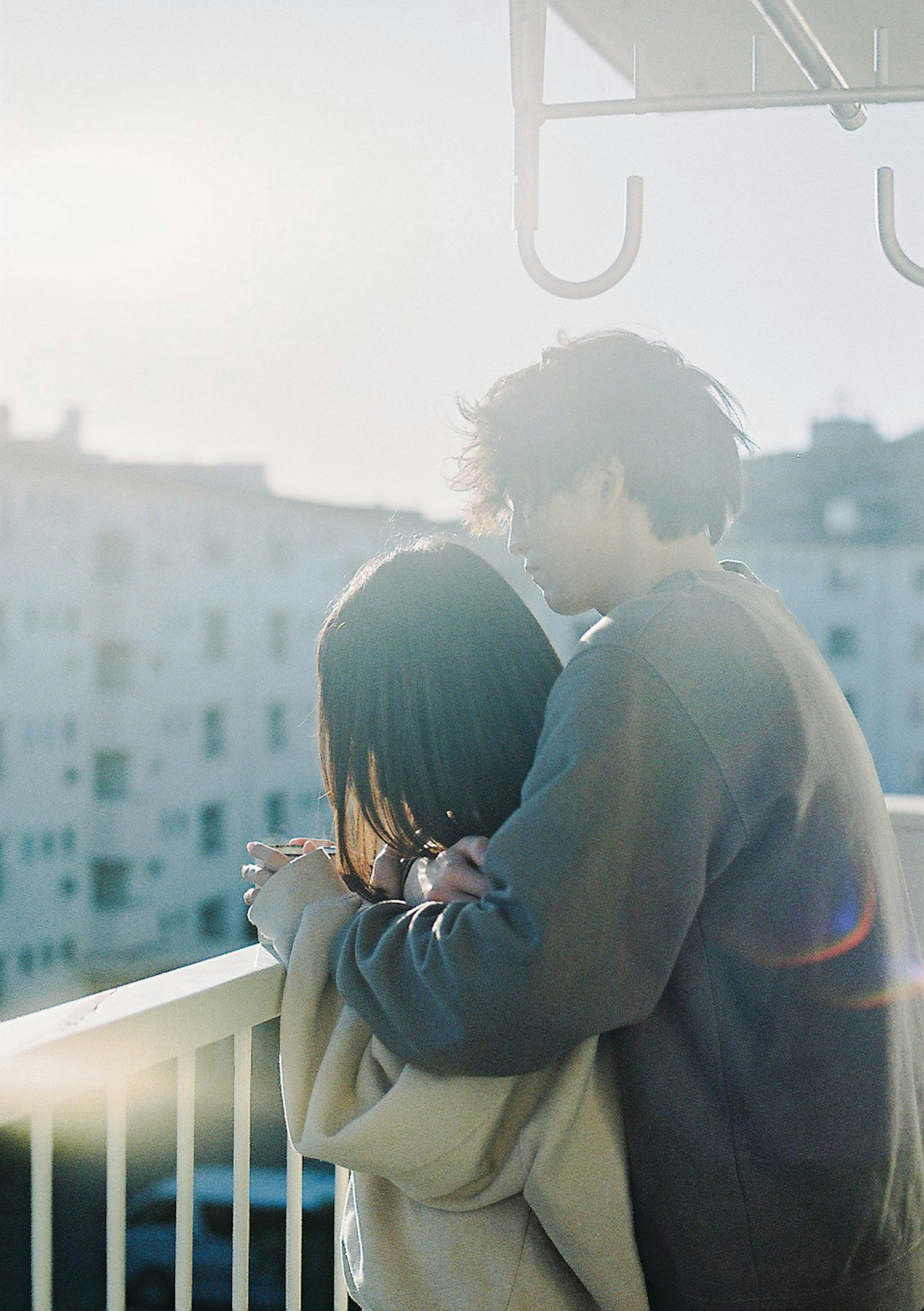 Couple embracing on a balcony with a soft sunlight