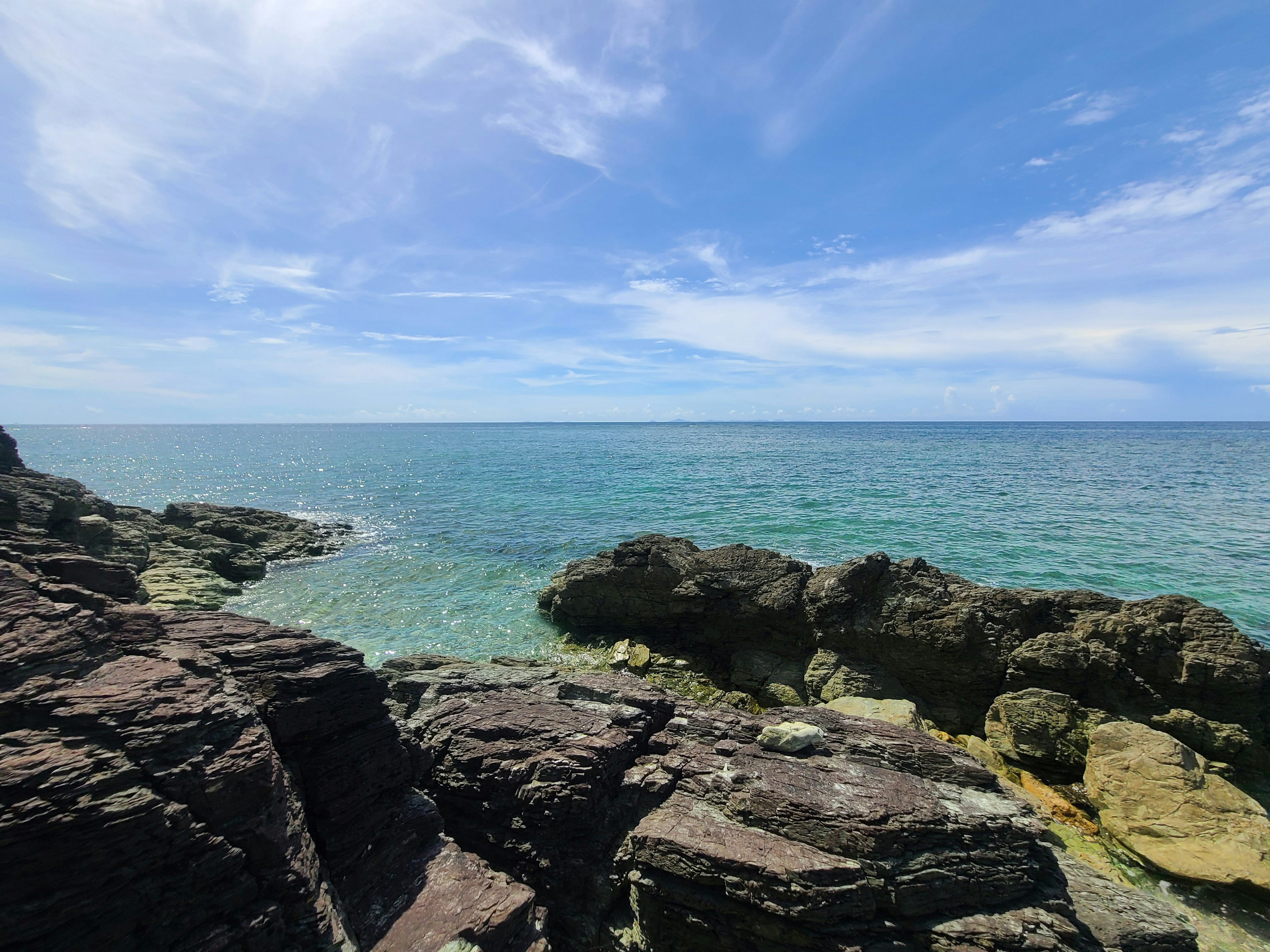 ชายหาดหินกับทะเลสีน้ำเงินใสและท้องฟ้าที่สดใส