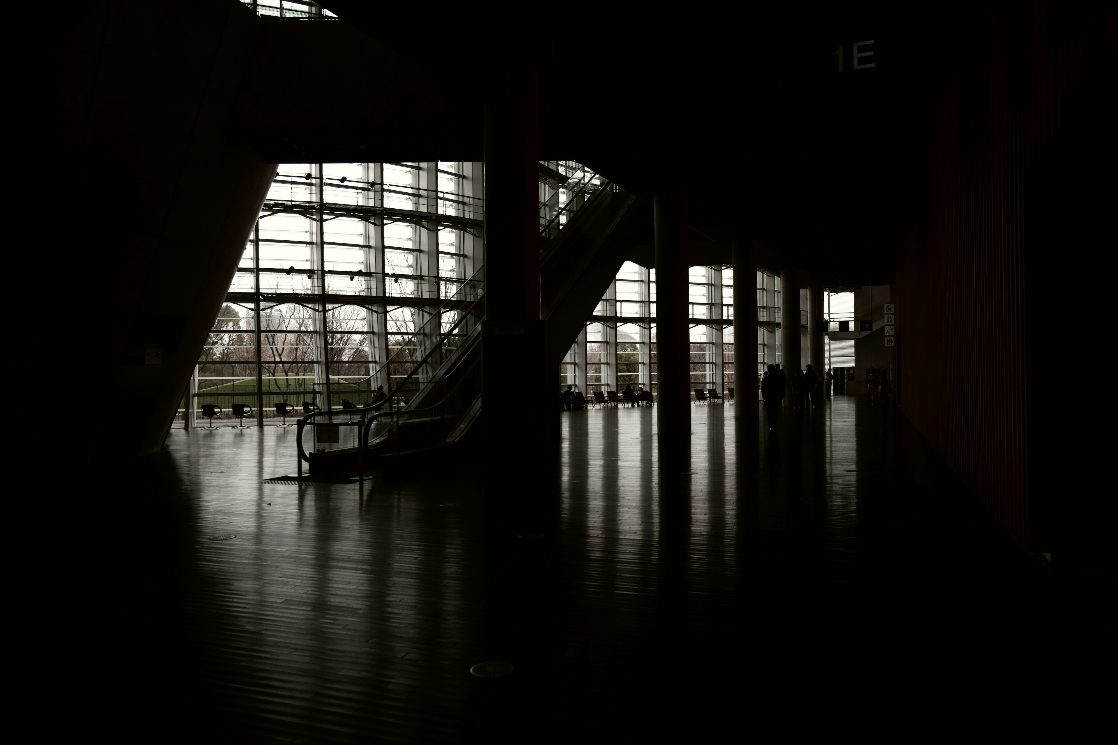 Interior oscuro con grandes ventanas y escaleras con suelo reflectante