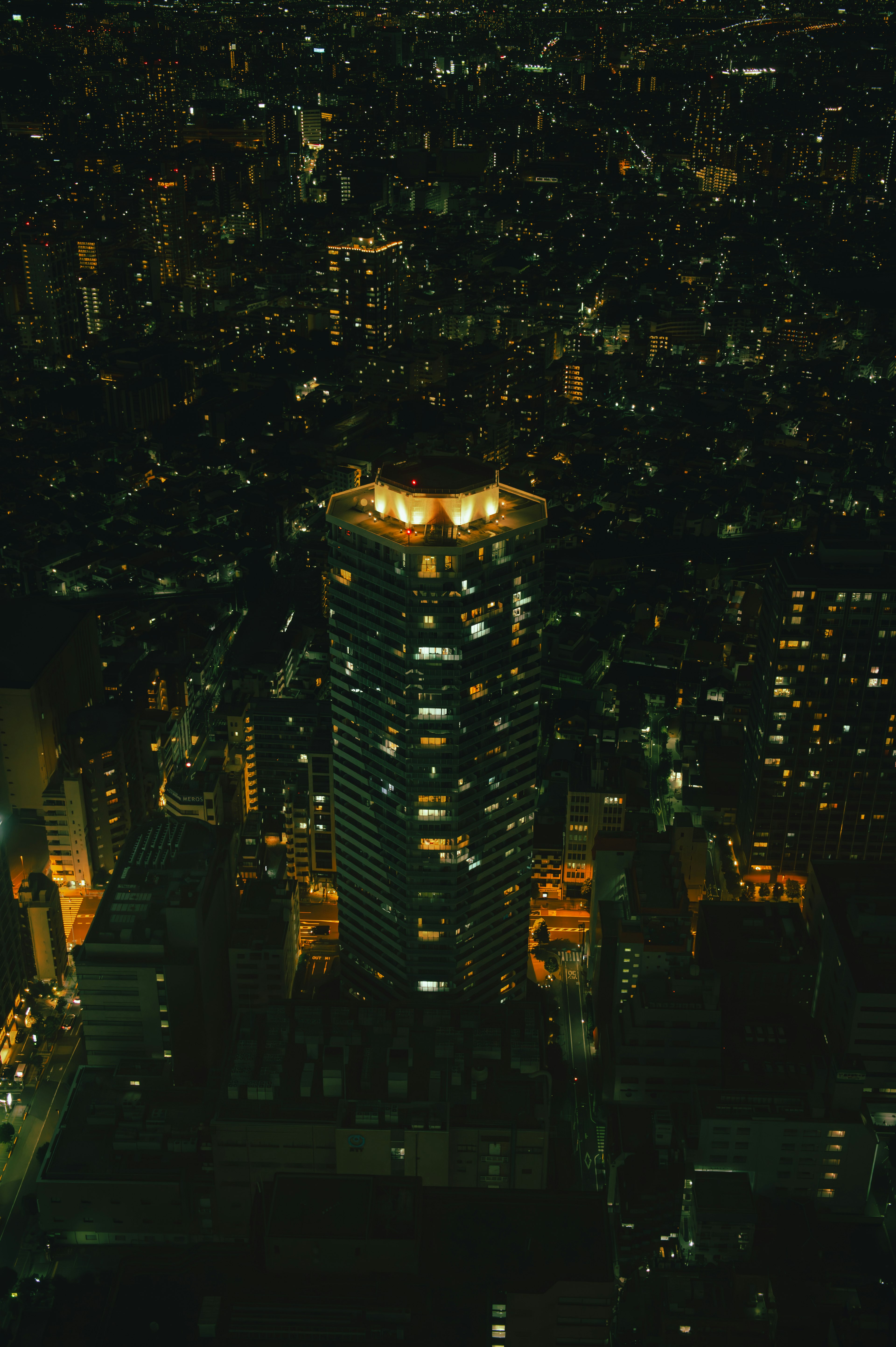 Aerial view of a city at night featuring a brightly lit building