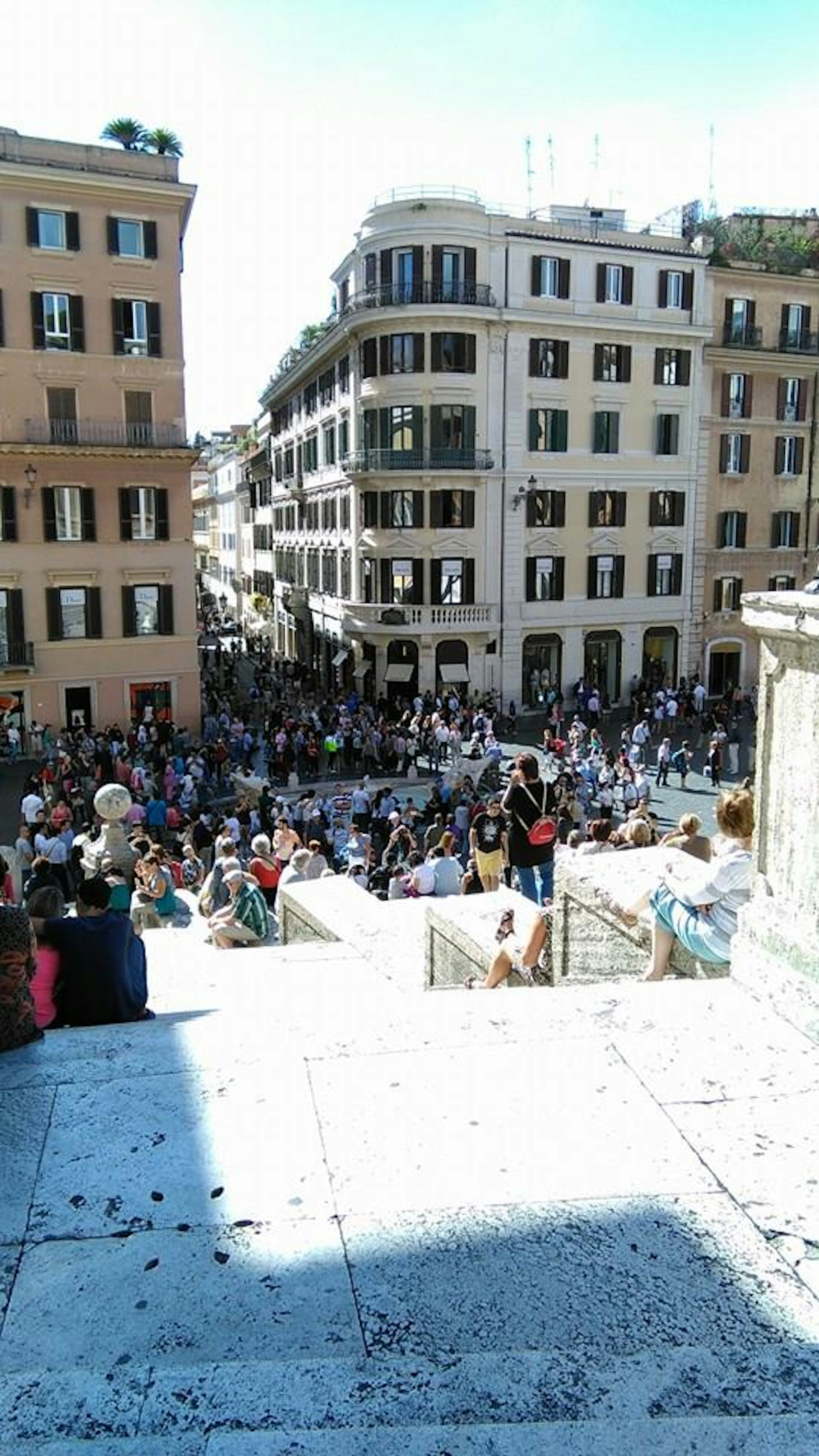 Crowd gathered at the Spanish Steps in Rome with surrounding buildings