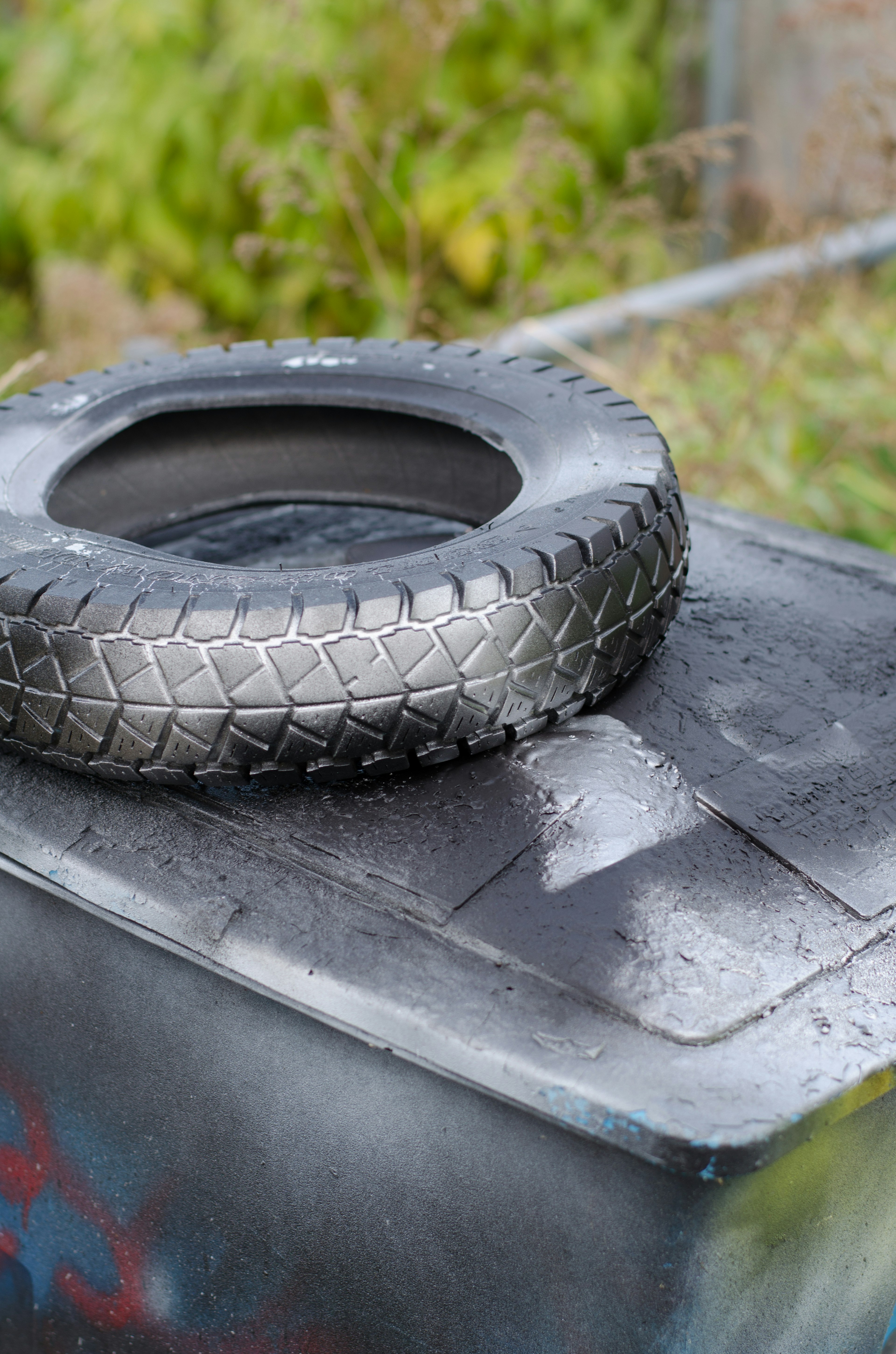 Image of a trash bin with a black tire placed on top