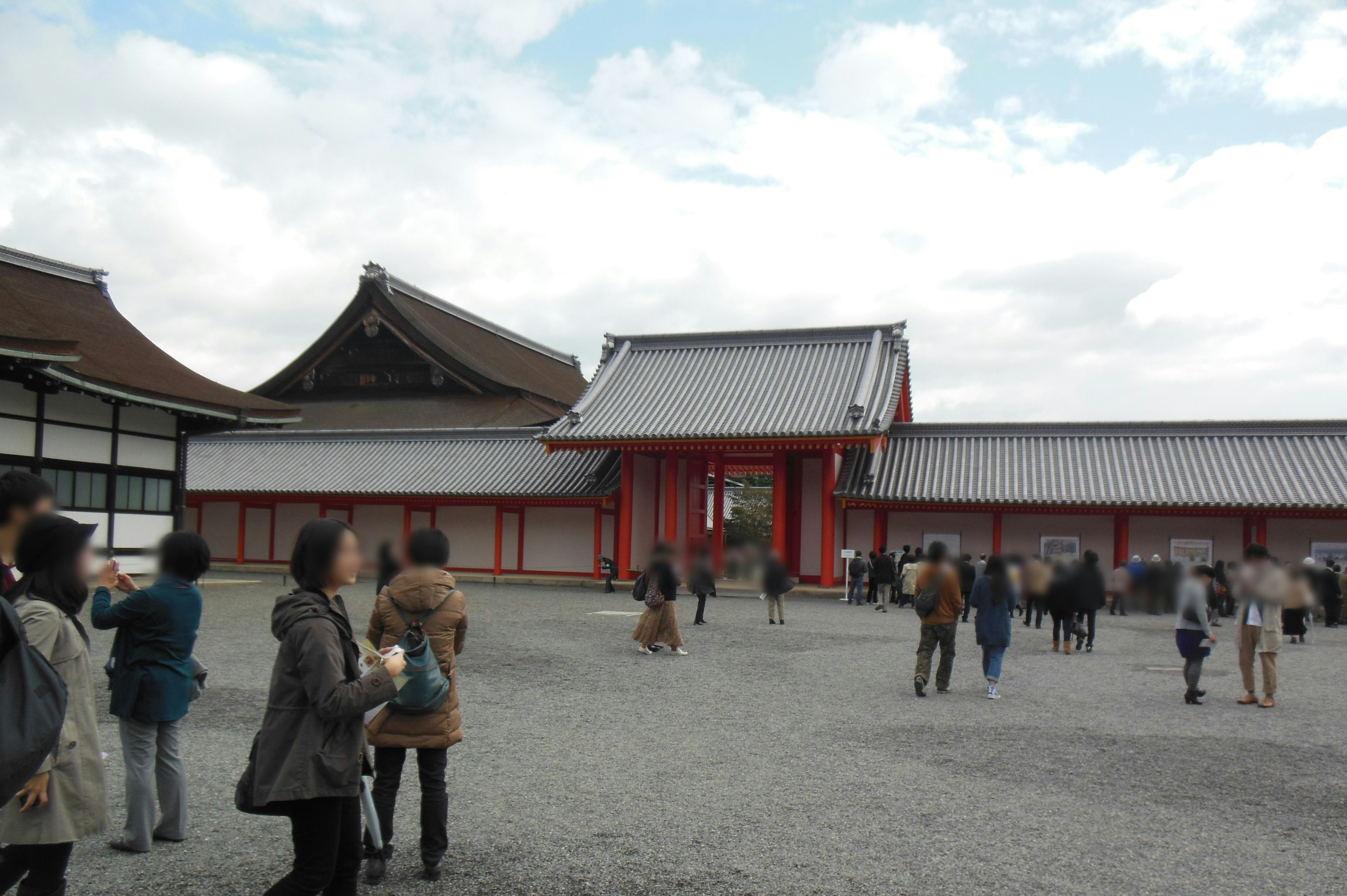 Touristen erkunden die Außenseite eines traditionellen japanischen Tempels mit einem roten Tor und historischen Gebäuden