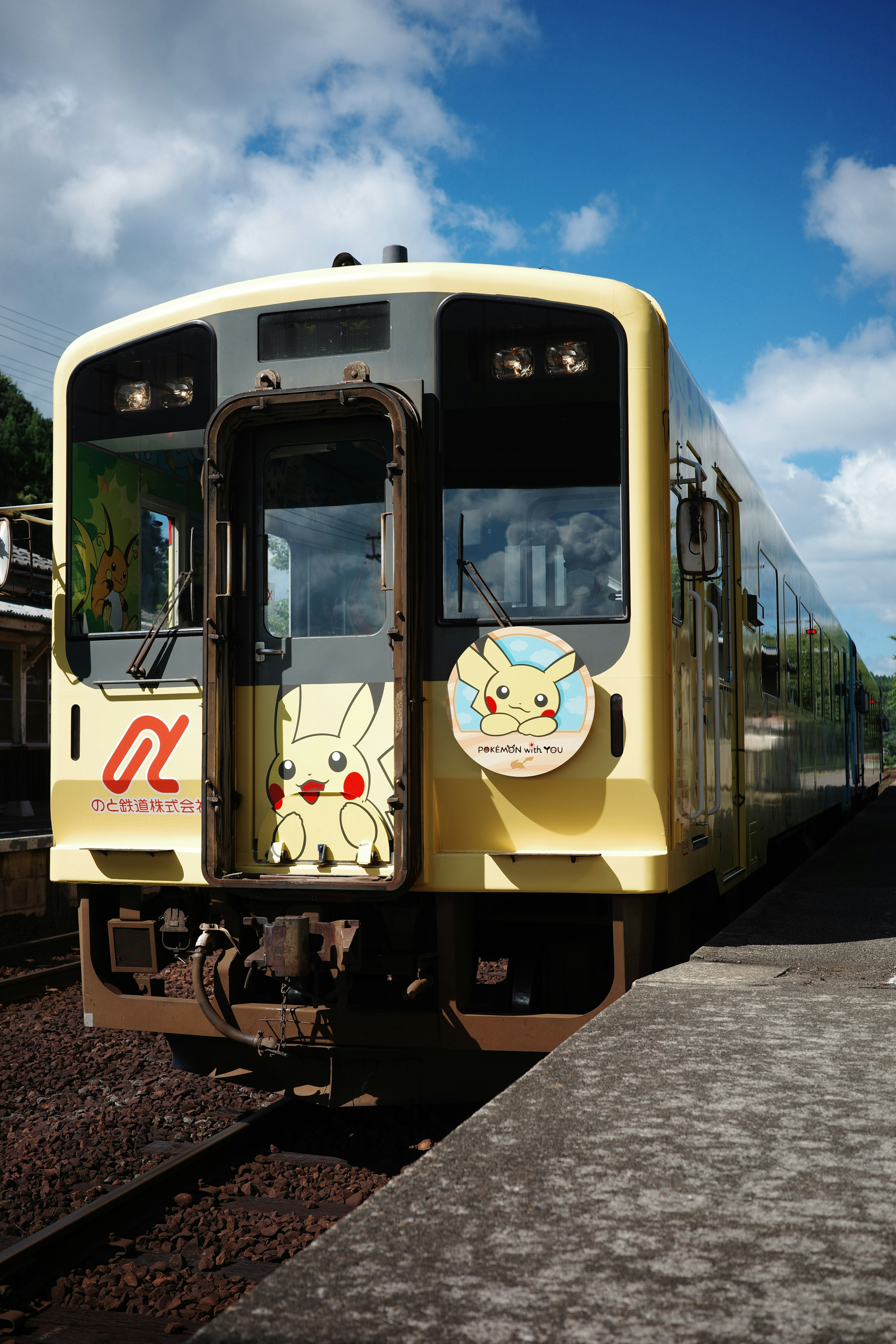 Un tren amarillo con un diseño de Pikachu está estacionado en una estación