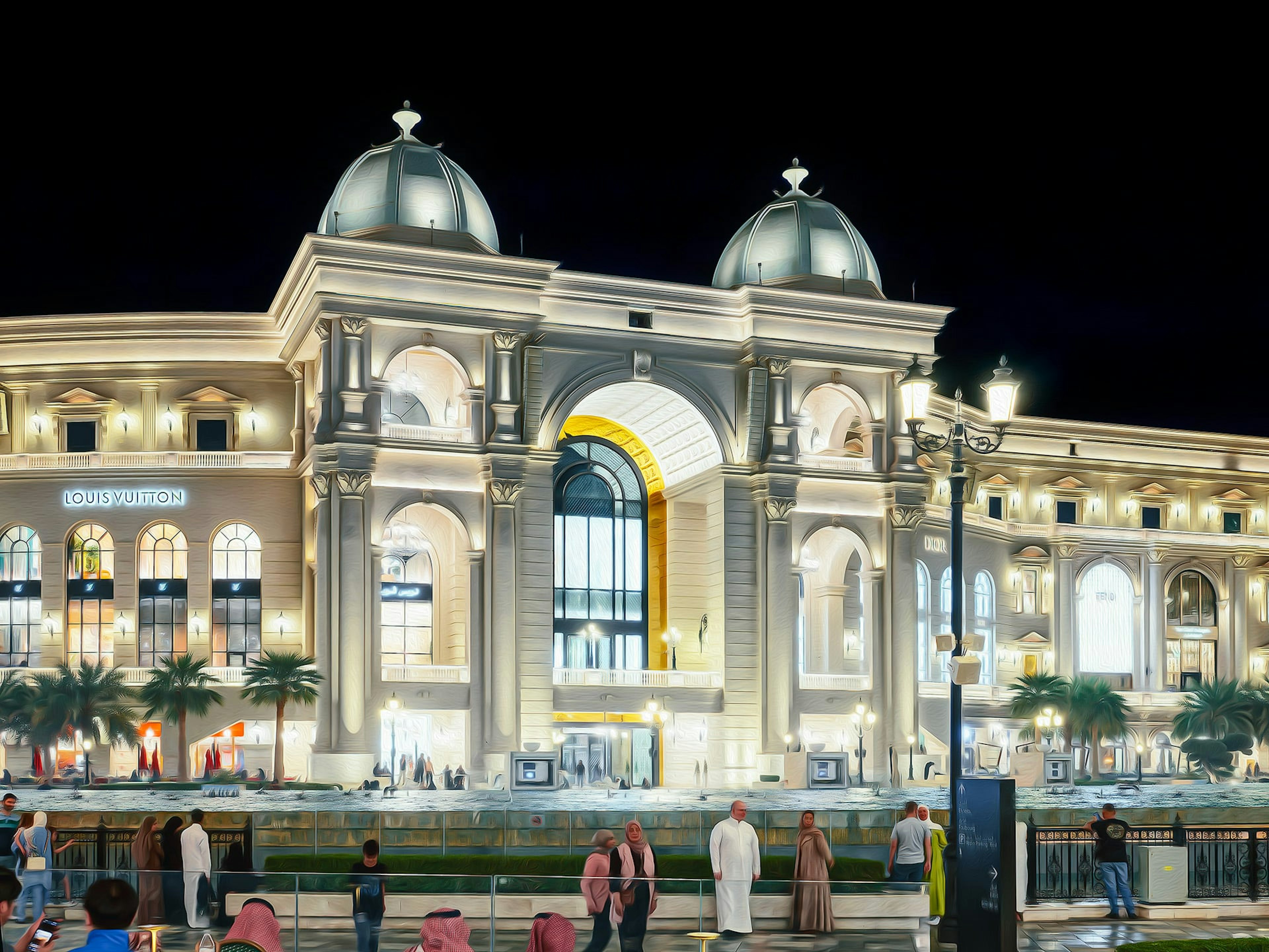 Bel extérieur de bâtiment la nuit avec des lumières brillantes et des toits en dôme grande entrée en arc et palmiers environnants