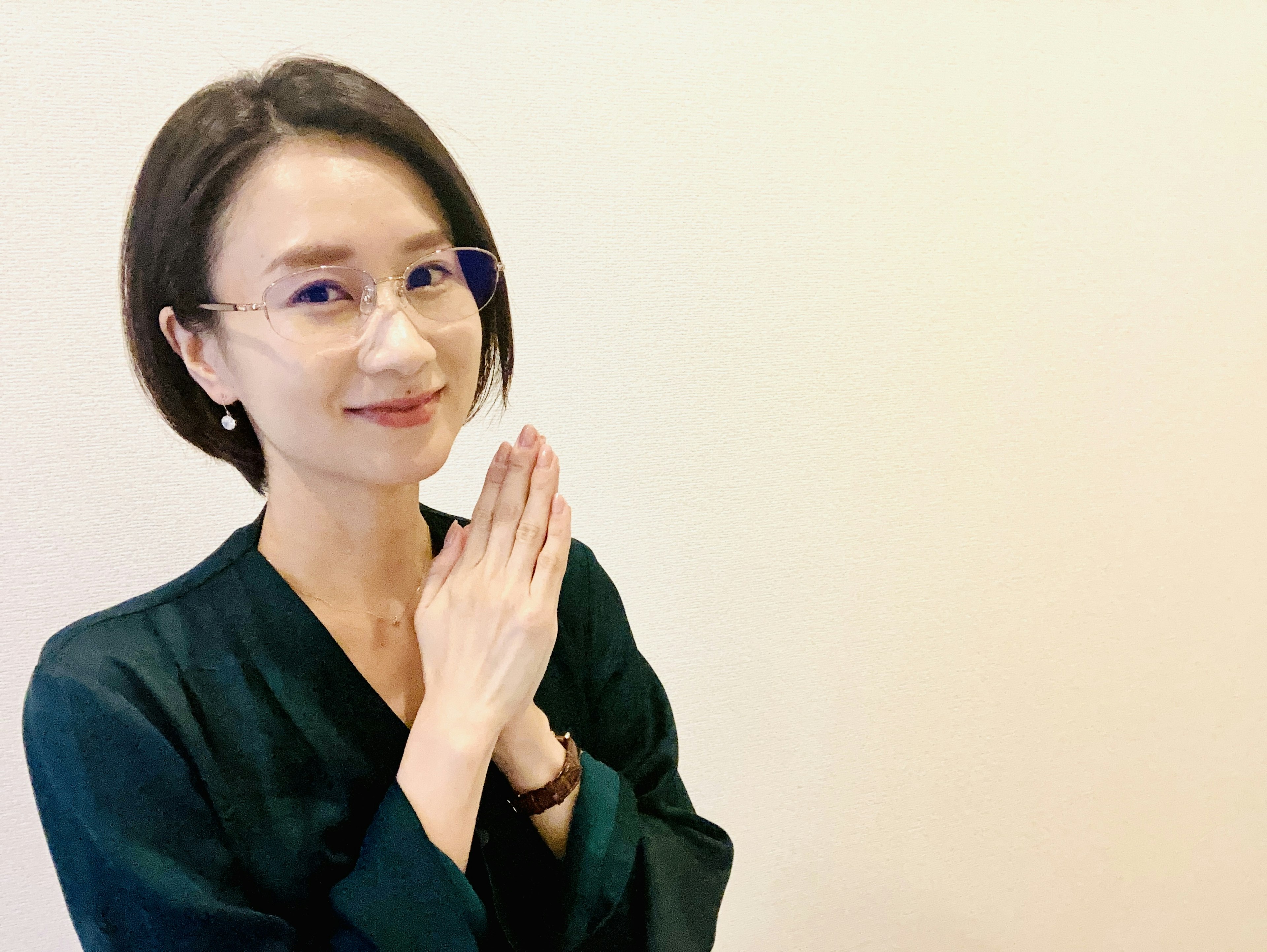 A woman with short hair smiling and putting her hands together