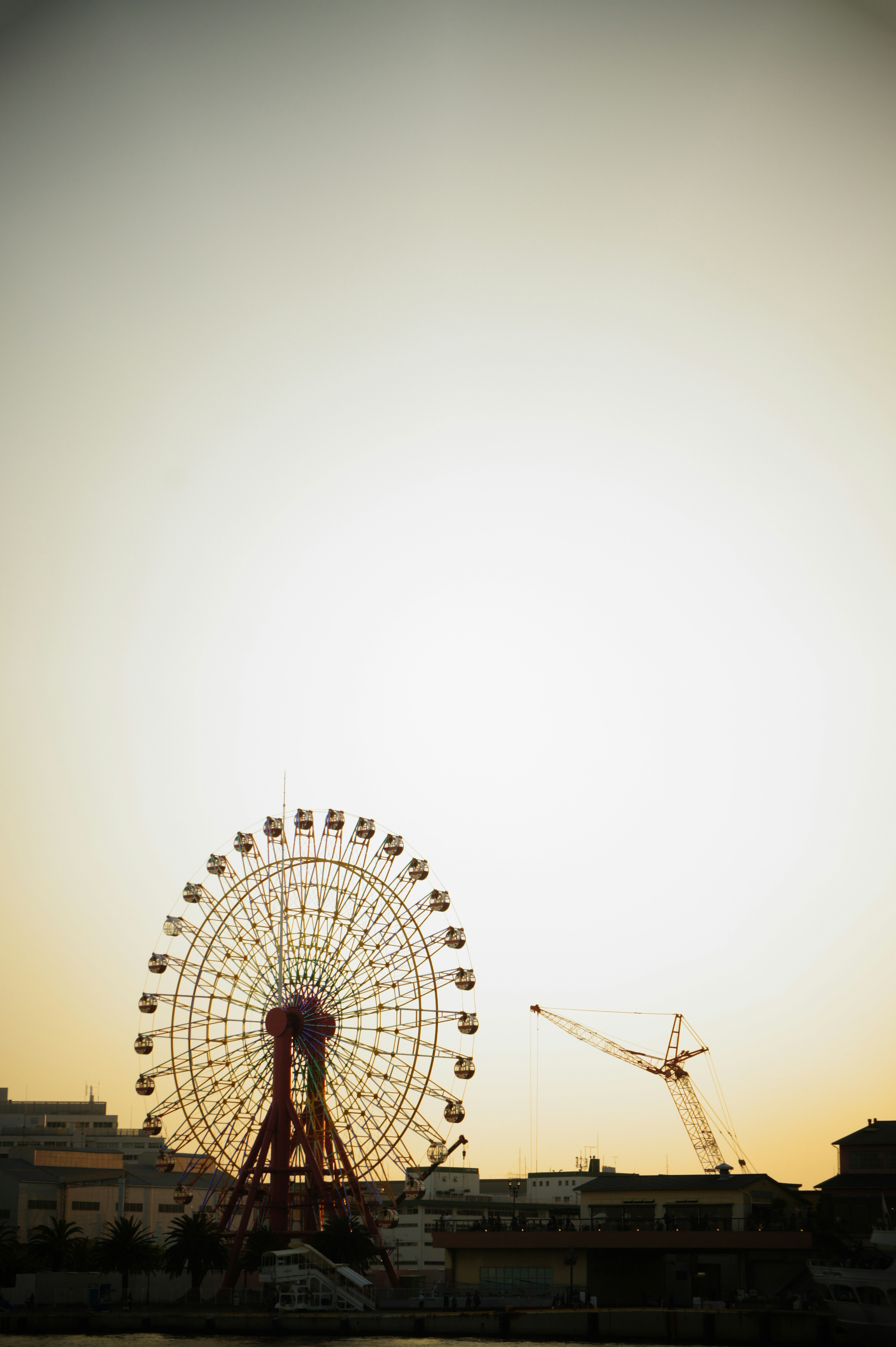 Ferris wheel and crane against a sunset sky