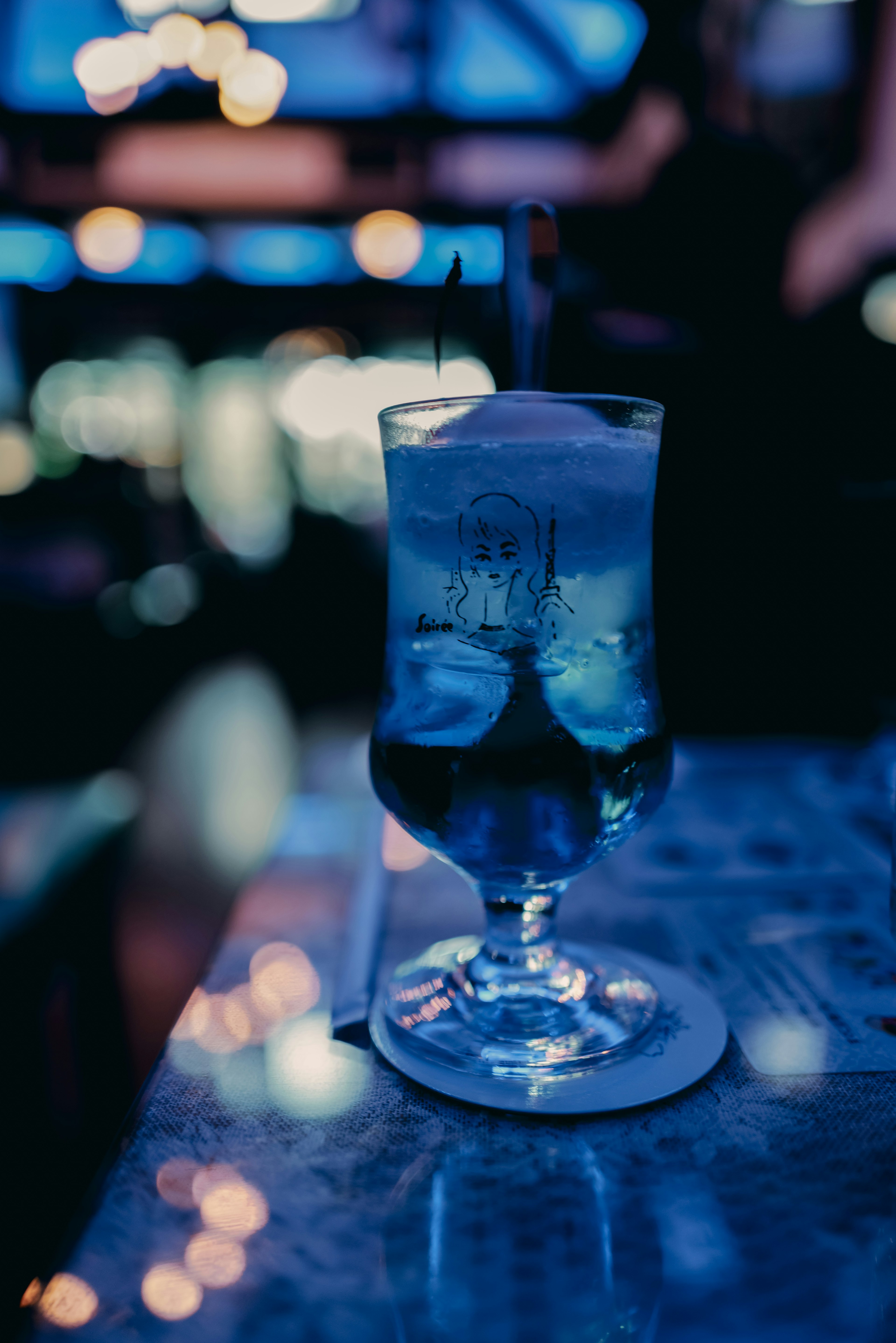 Cóctel azul en un vaso sobre una mesa de bar por la noche