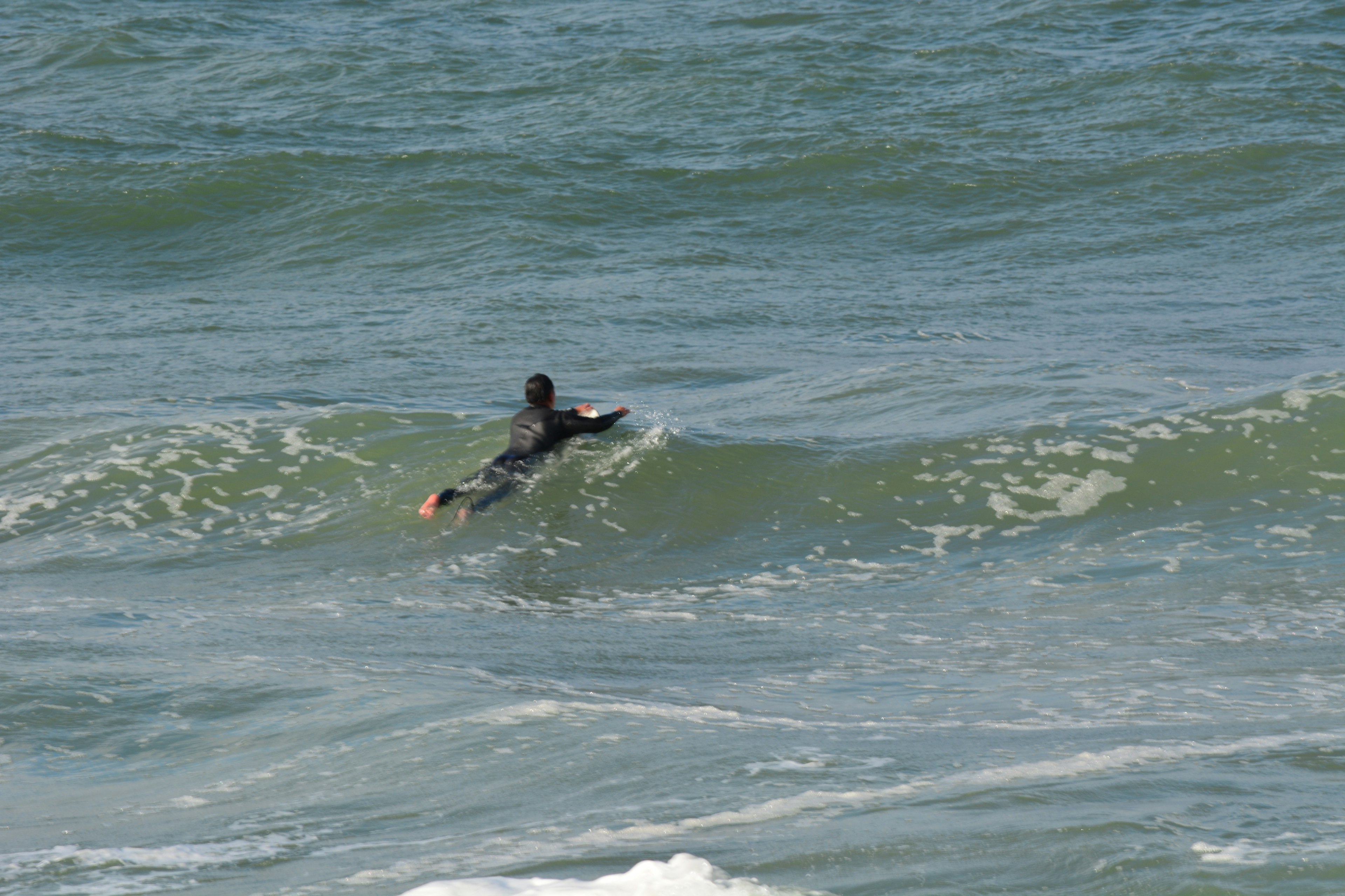 Surfista in una muta nera che cavalca un'onda nell'oceano