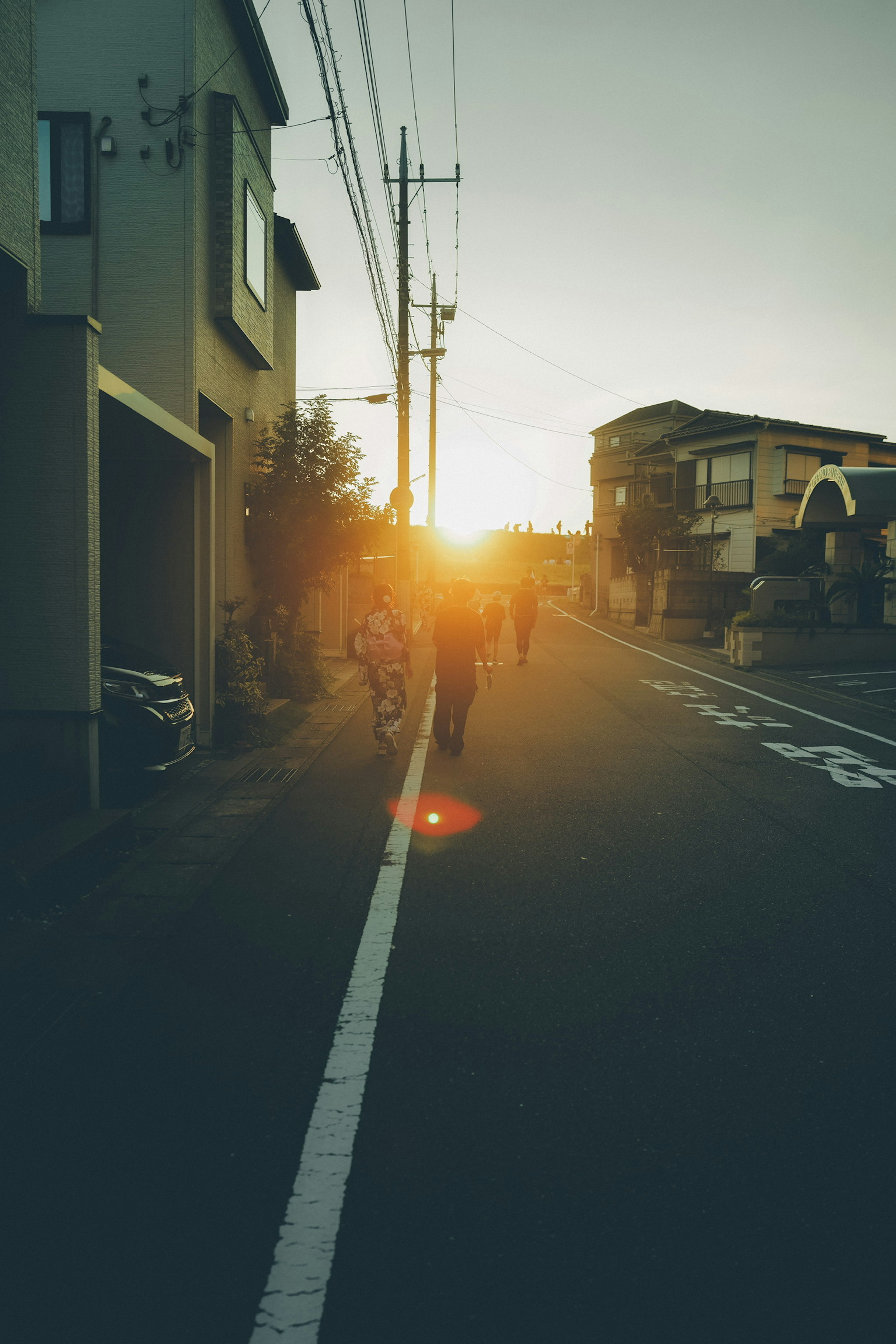 Personas caminando en una zona residencial tranquila iluminada por la puesta de sol