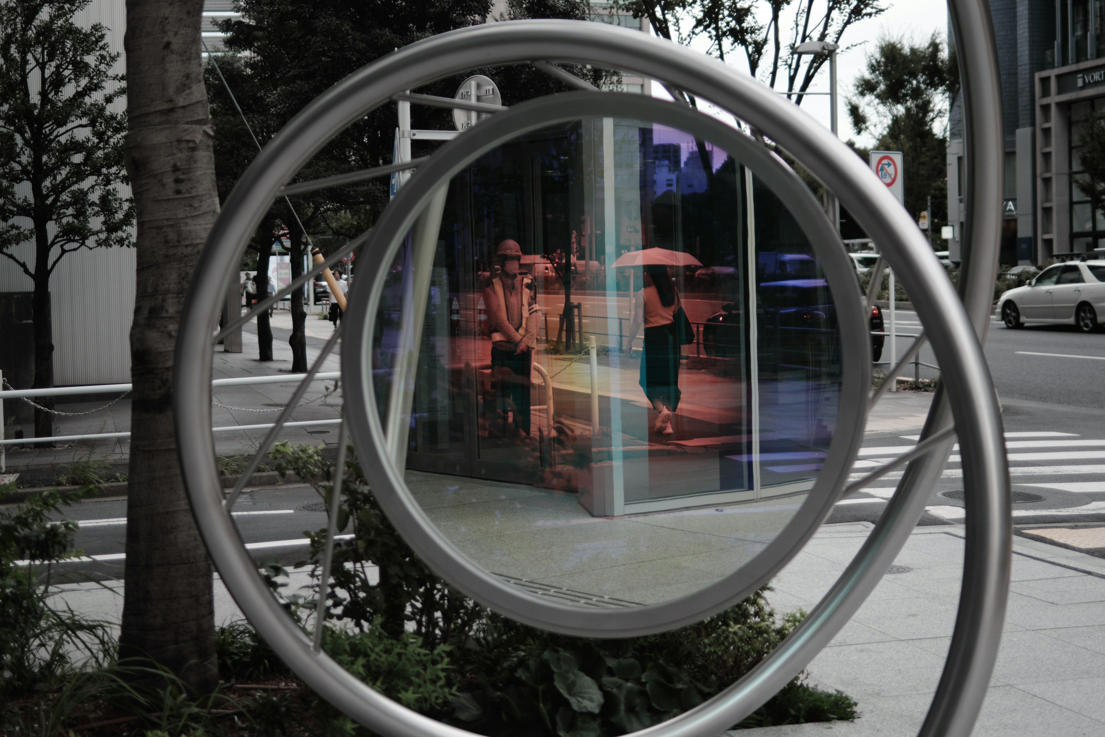 Personas reflejadas en un gran anillo de metal que muestra una escena urbana