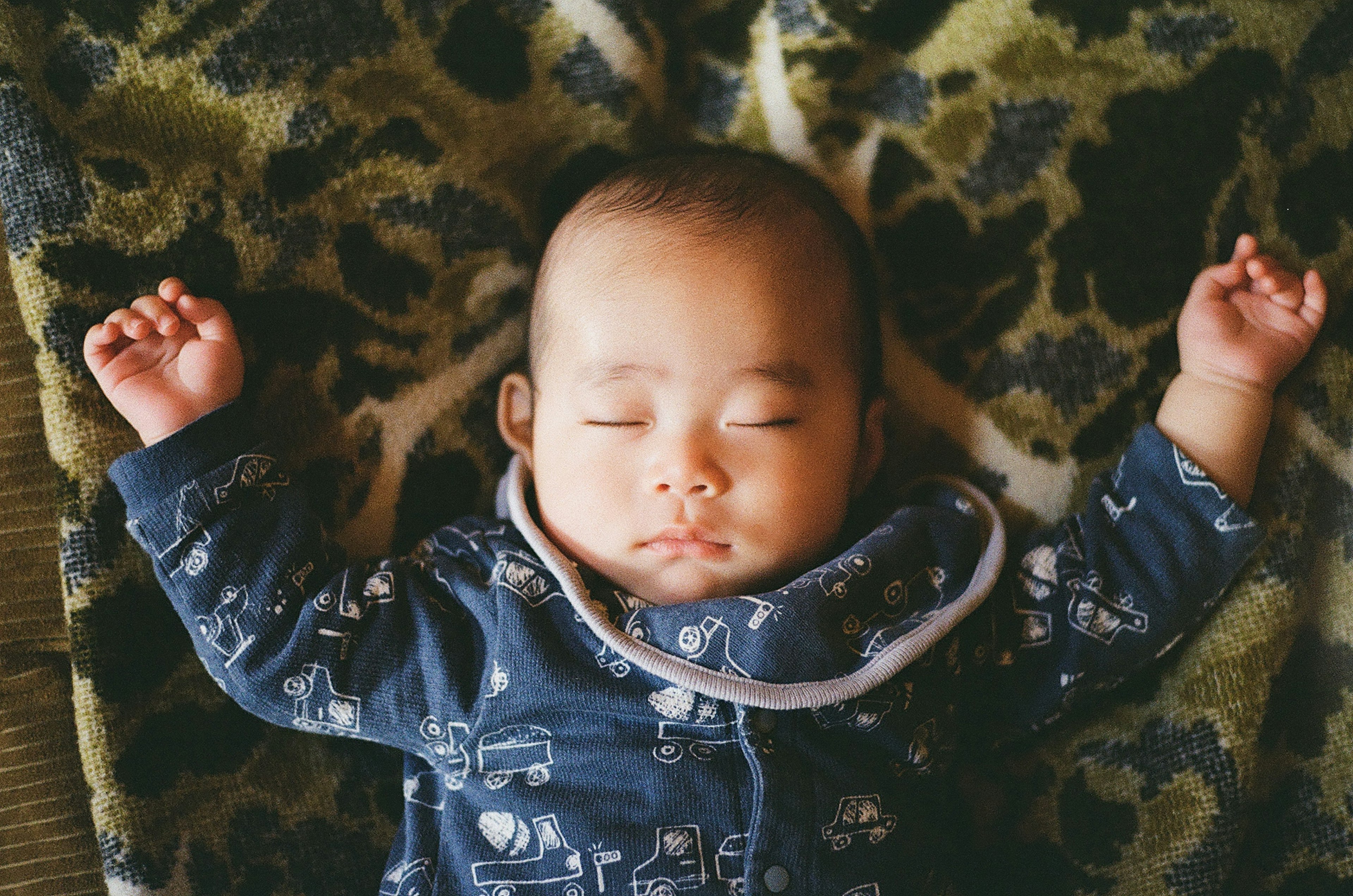 Bayi tidur nyenyak mengenakan piyama biru di atas selimut yang nyaman