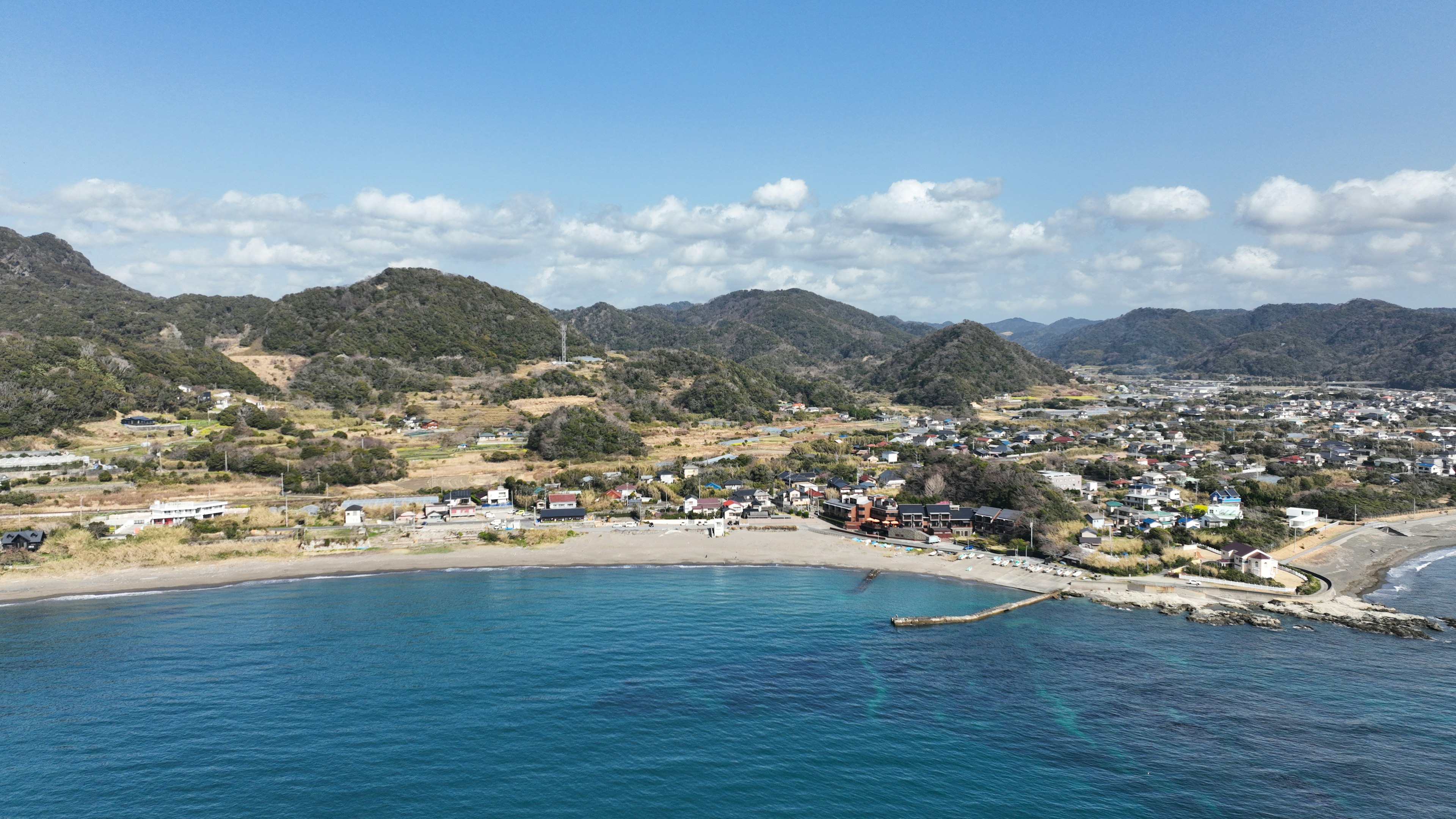 Costa panoramica con oceano blu, villaggio tranquillo e montagne sullo sfondo