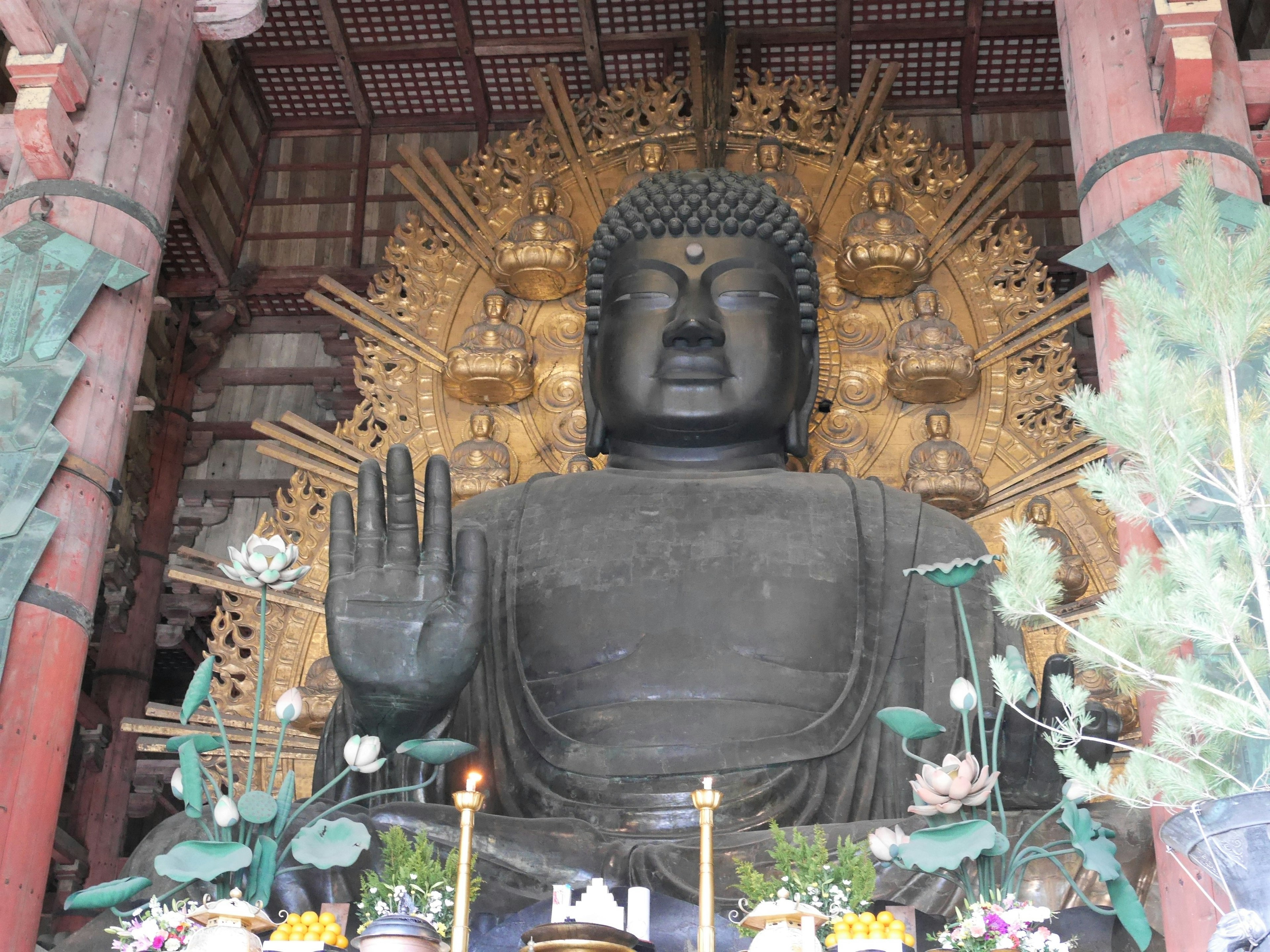 Large Buddha statue with raised hand and golden backdrop