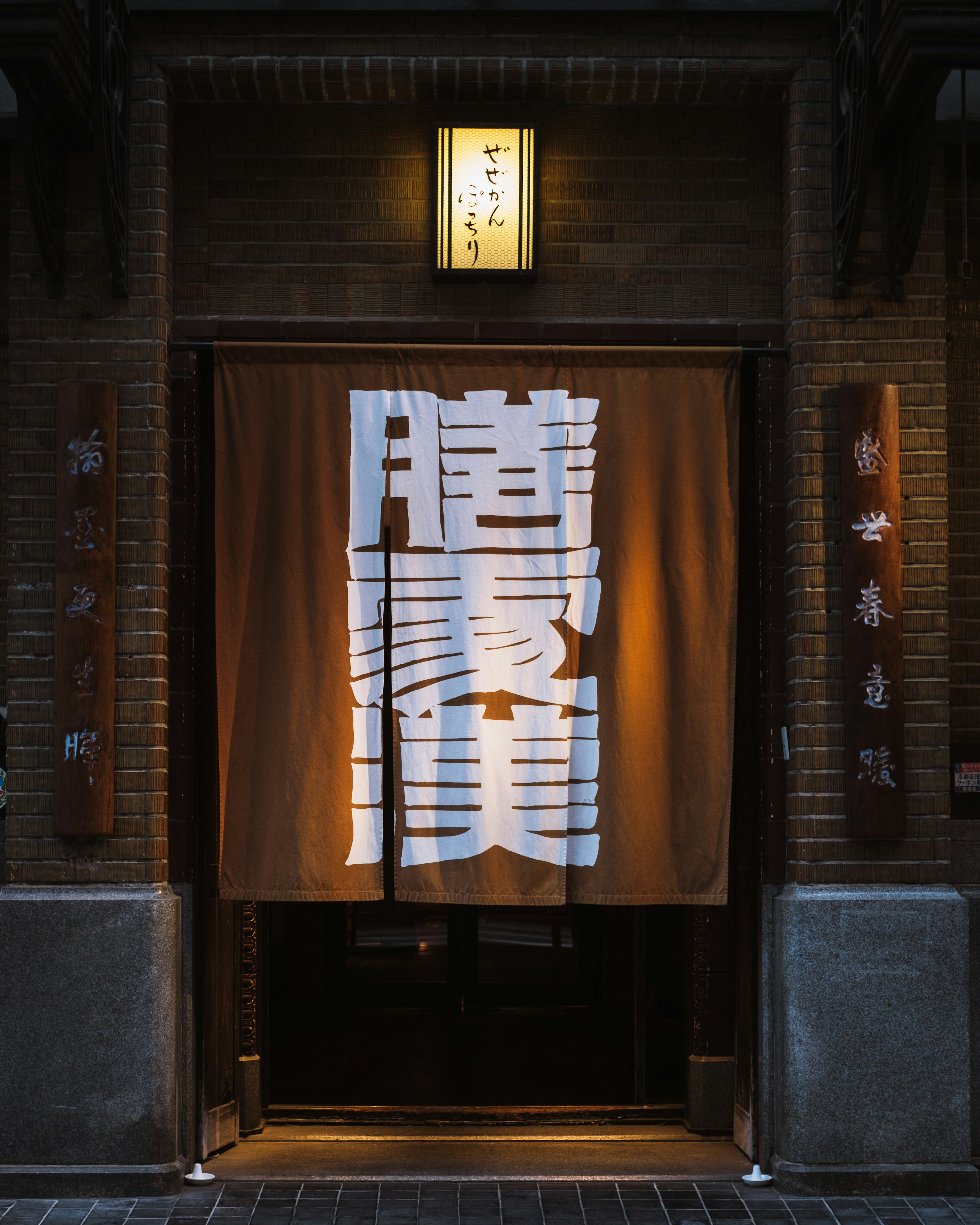 Entrance with a large white noren curtain and warm lighting