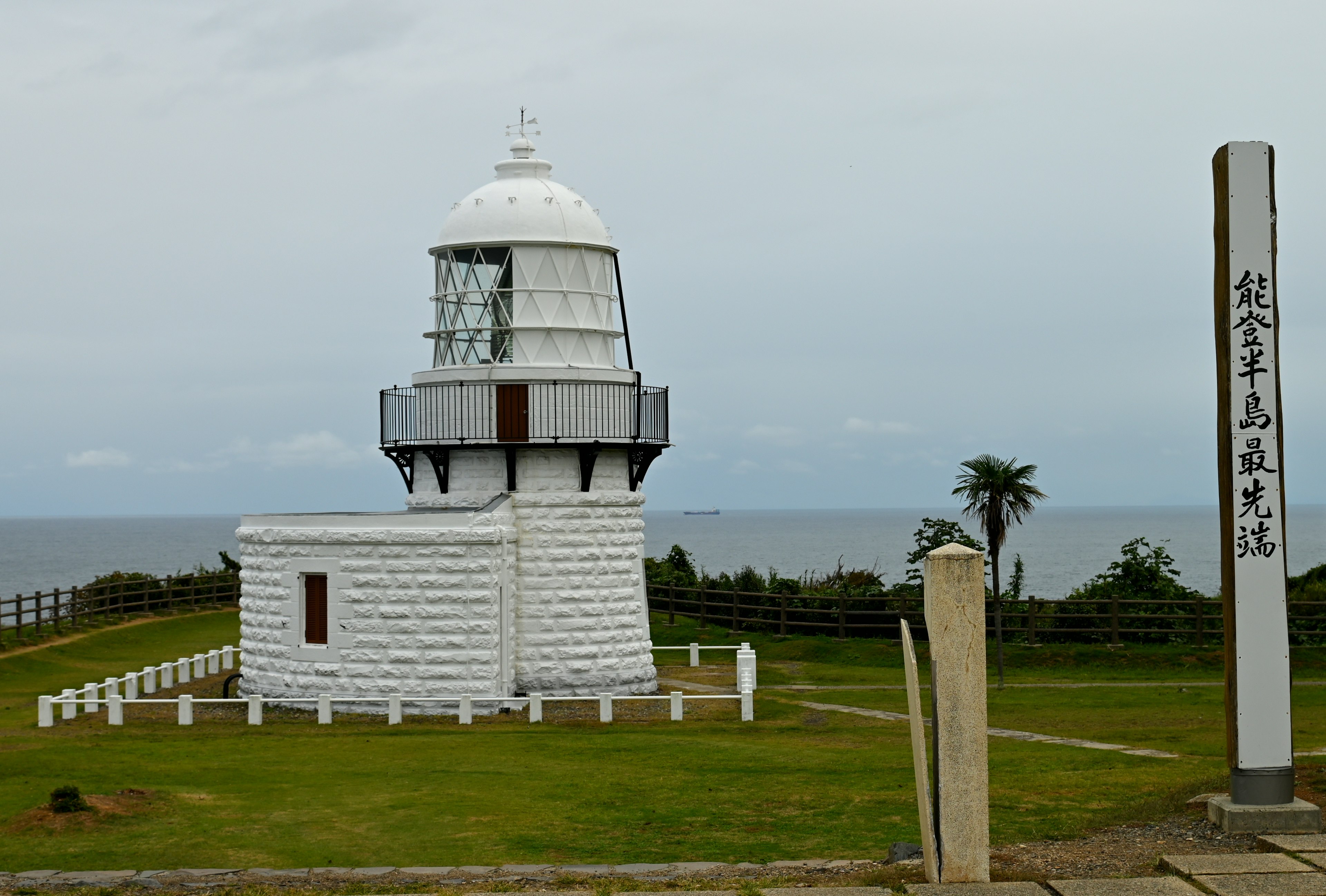 Weißer Leuchtturm mit Meerblick und Rasenfläche