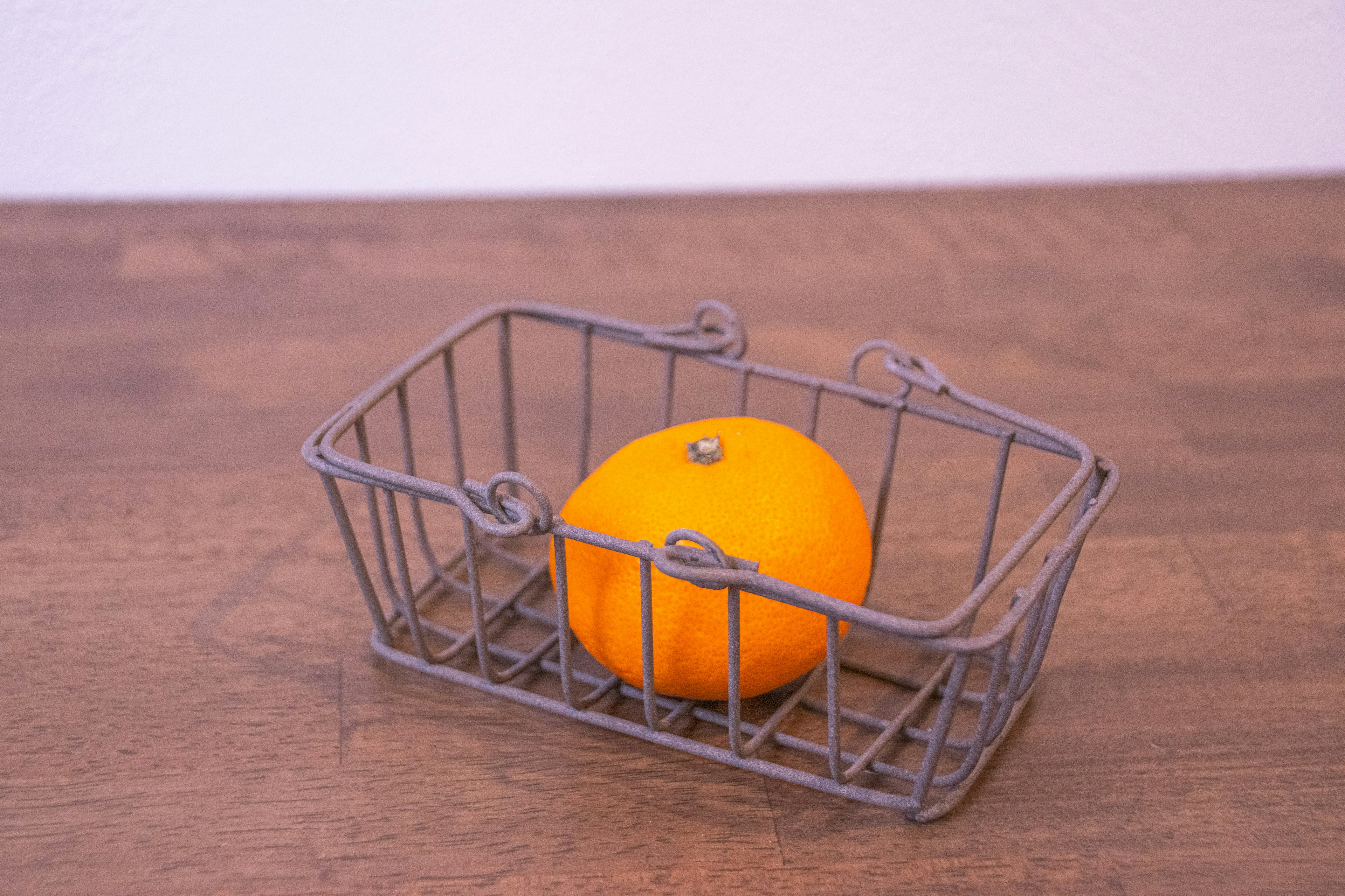 A small metal basket with an orange inside