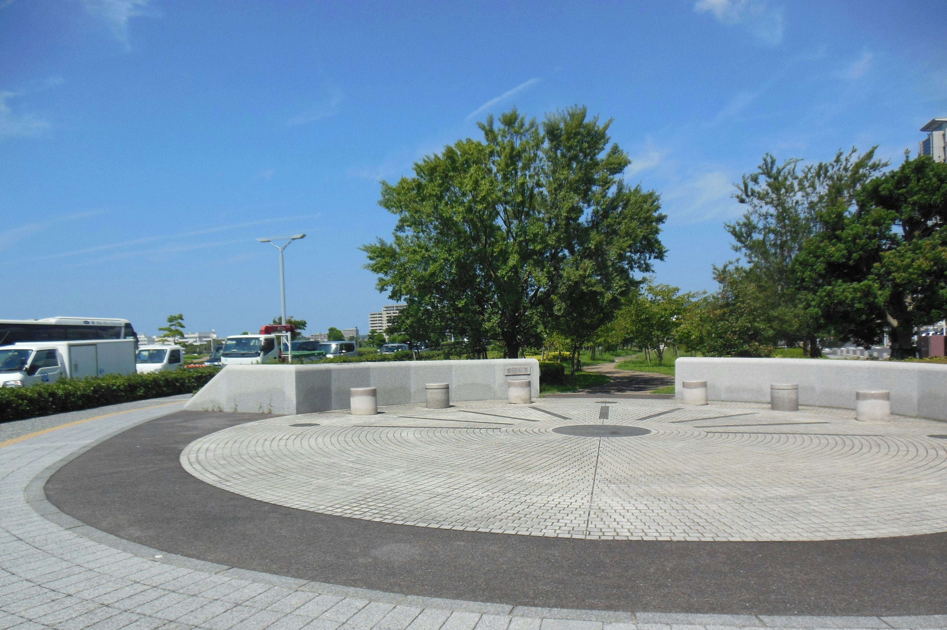 Circular plaza with benches and green trees under a blue sky